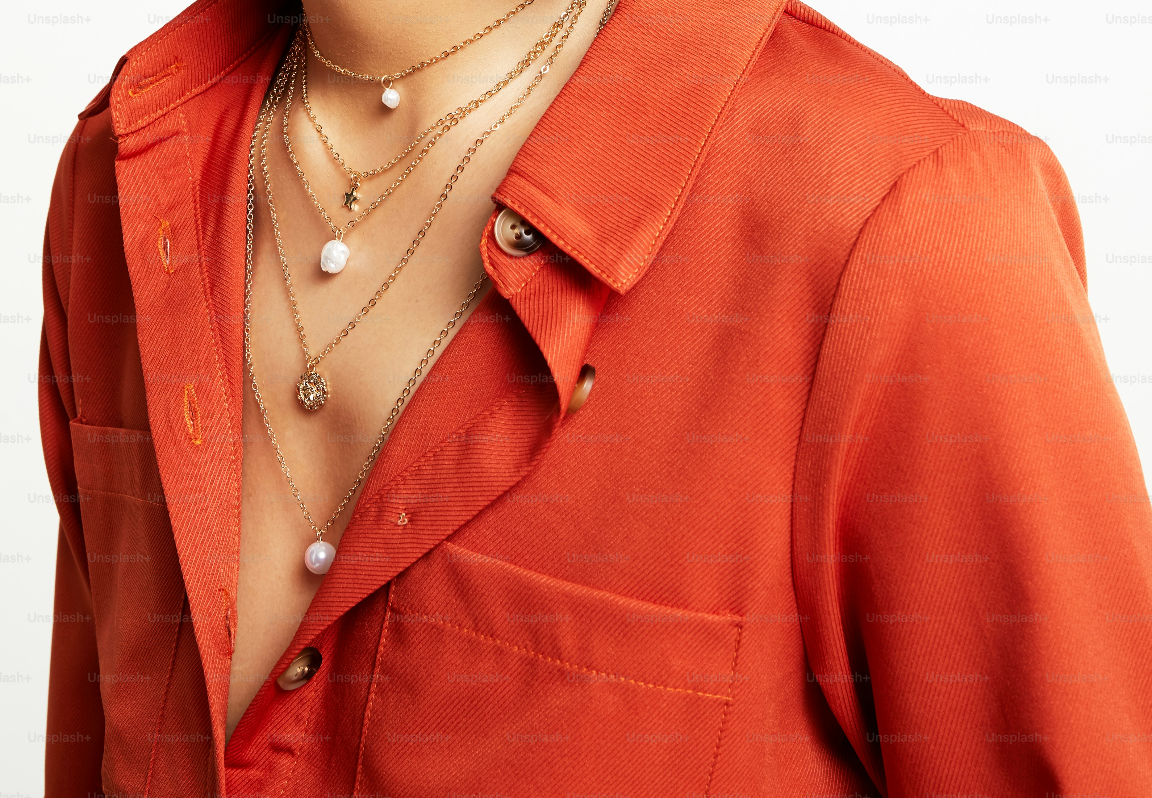 A man in an orange shirt with a pearl necklace