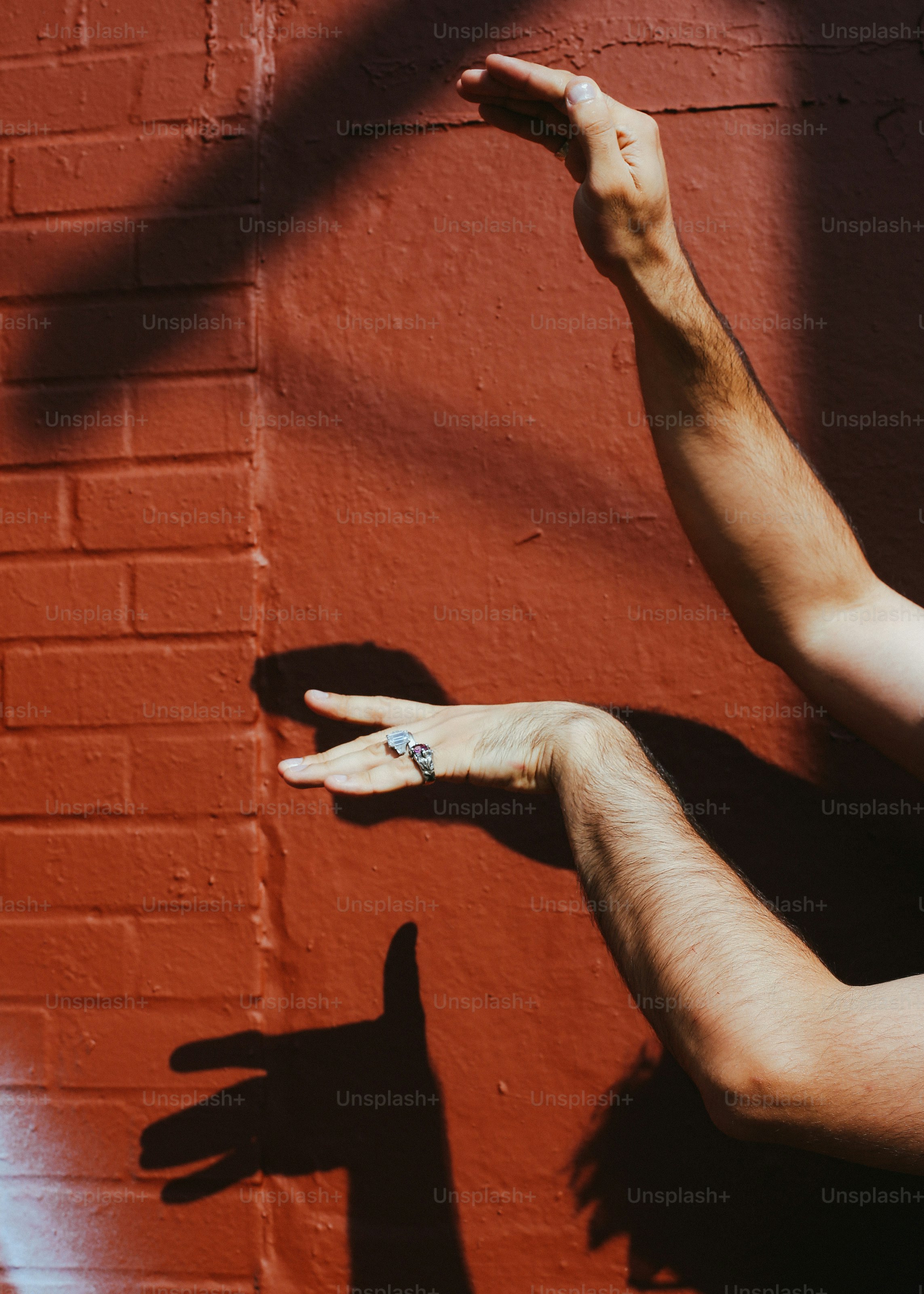 A shadow of a person reaching up towards a brick wall