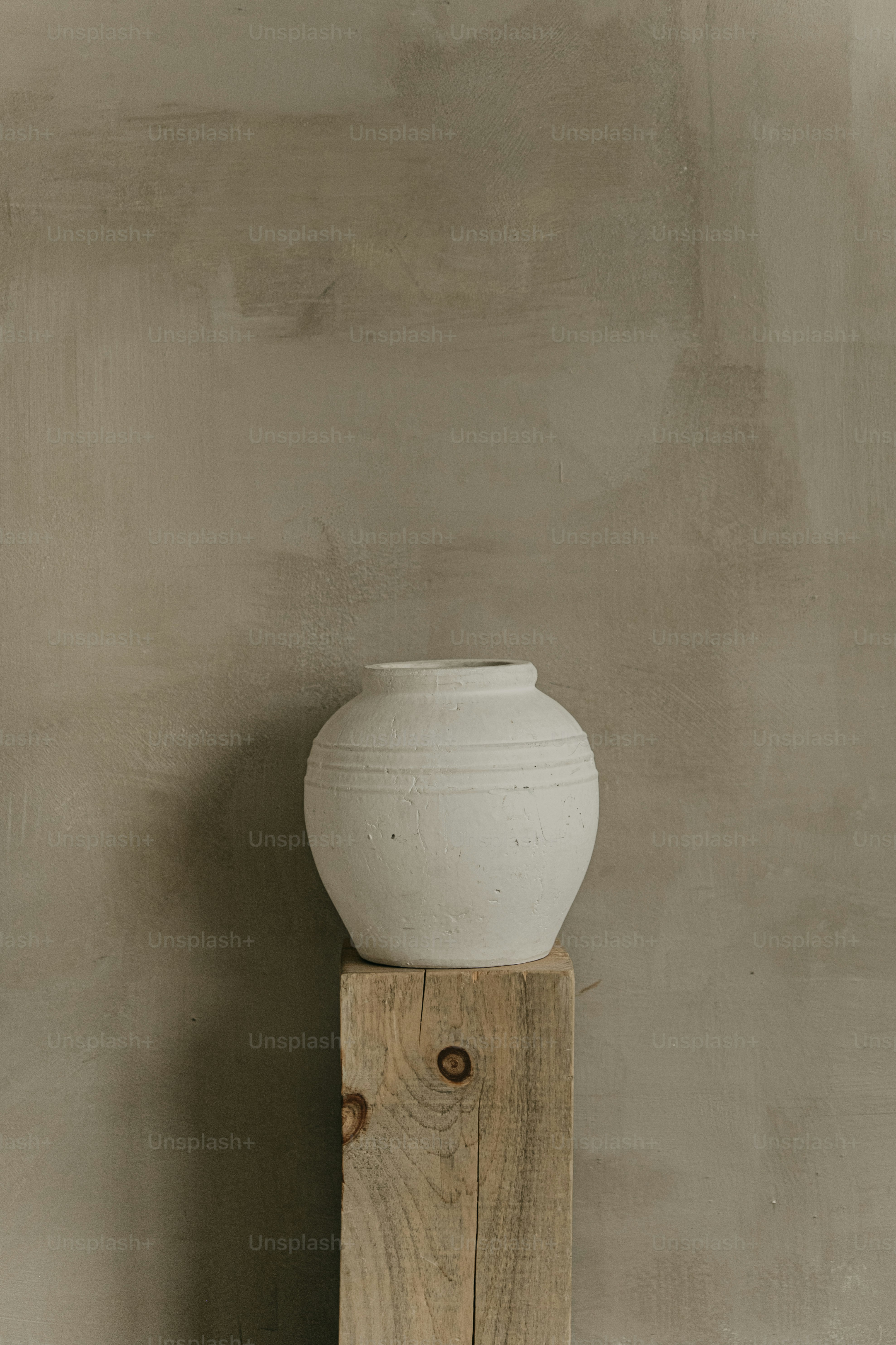 A white vase sitting on top of a wooden block
