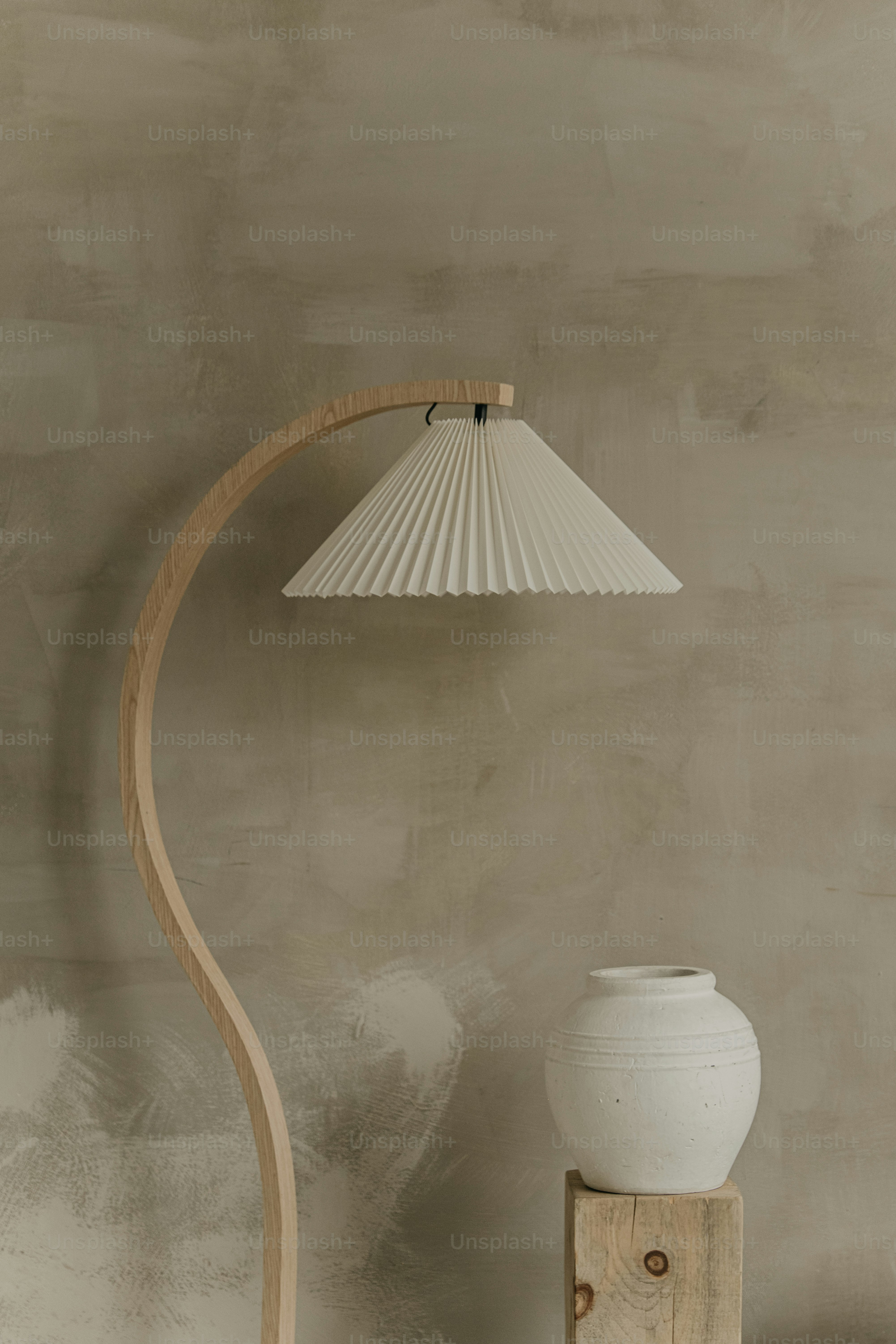 A white vase sitting on top of a table next to a lamp