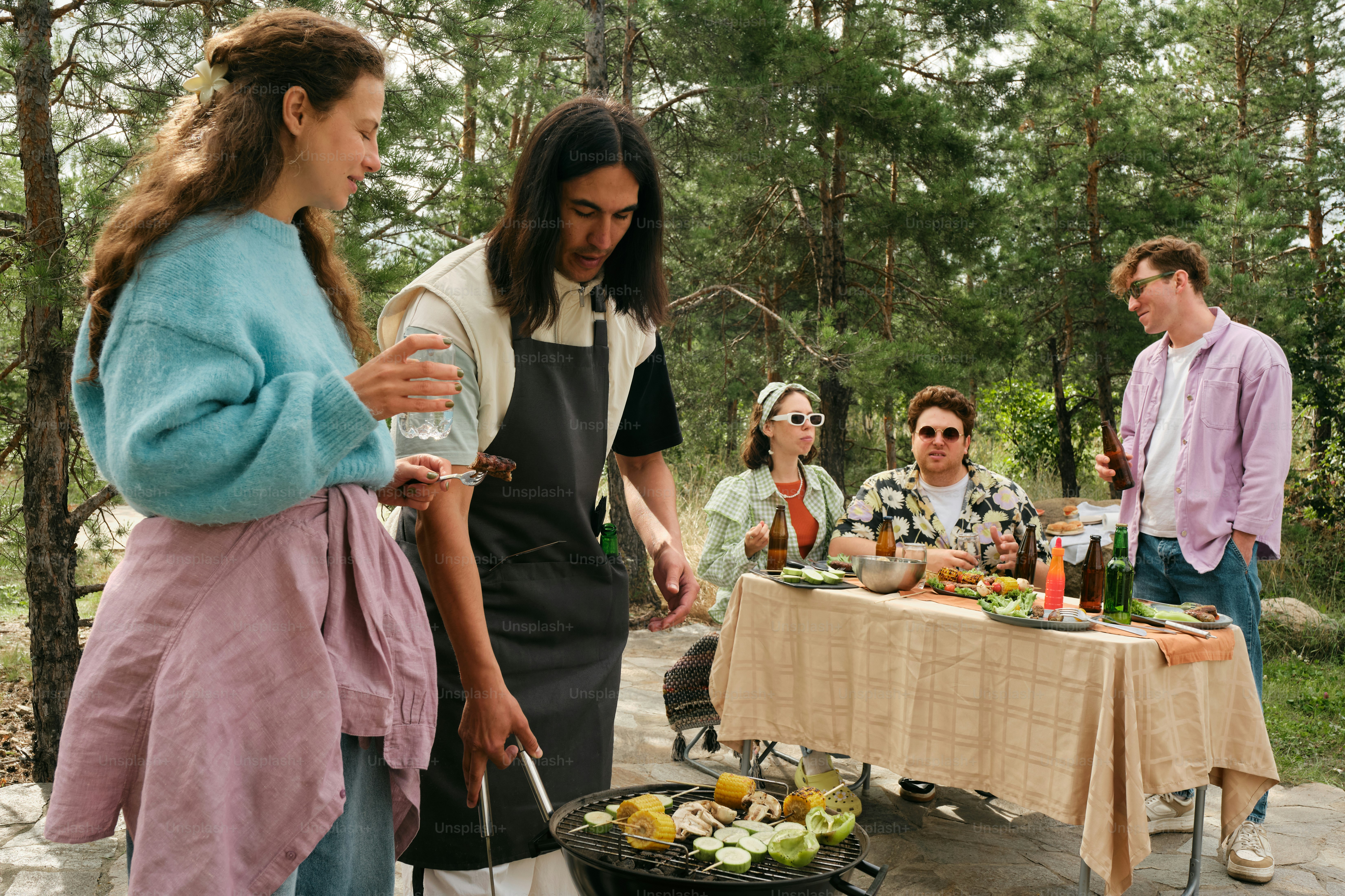 A group of people standing around a table with food on it photo ...