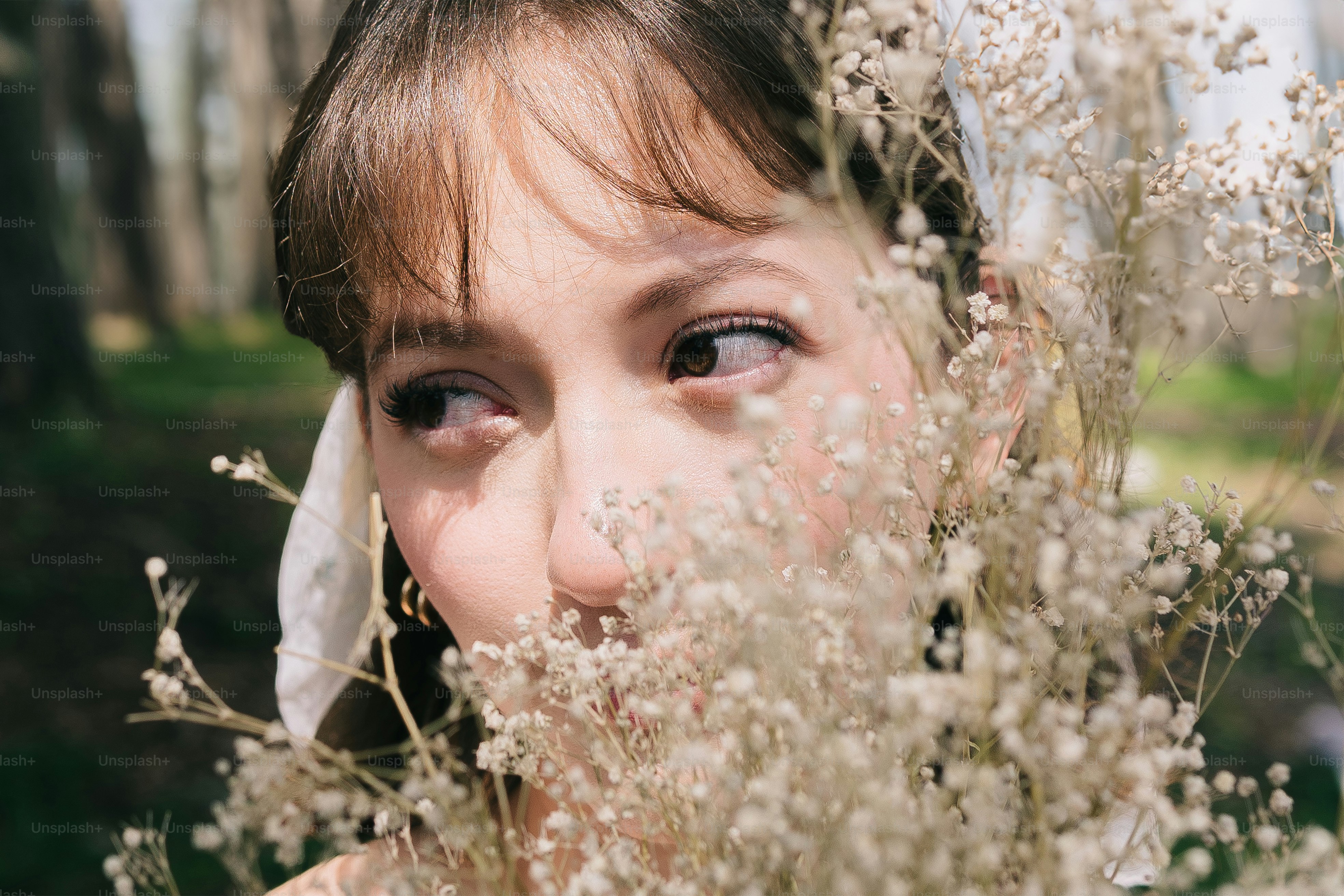 A young girl holding a bunch of flowers in front of her face photo ...
