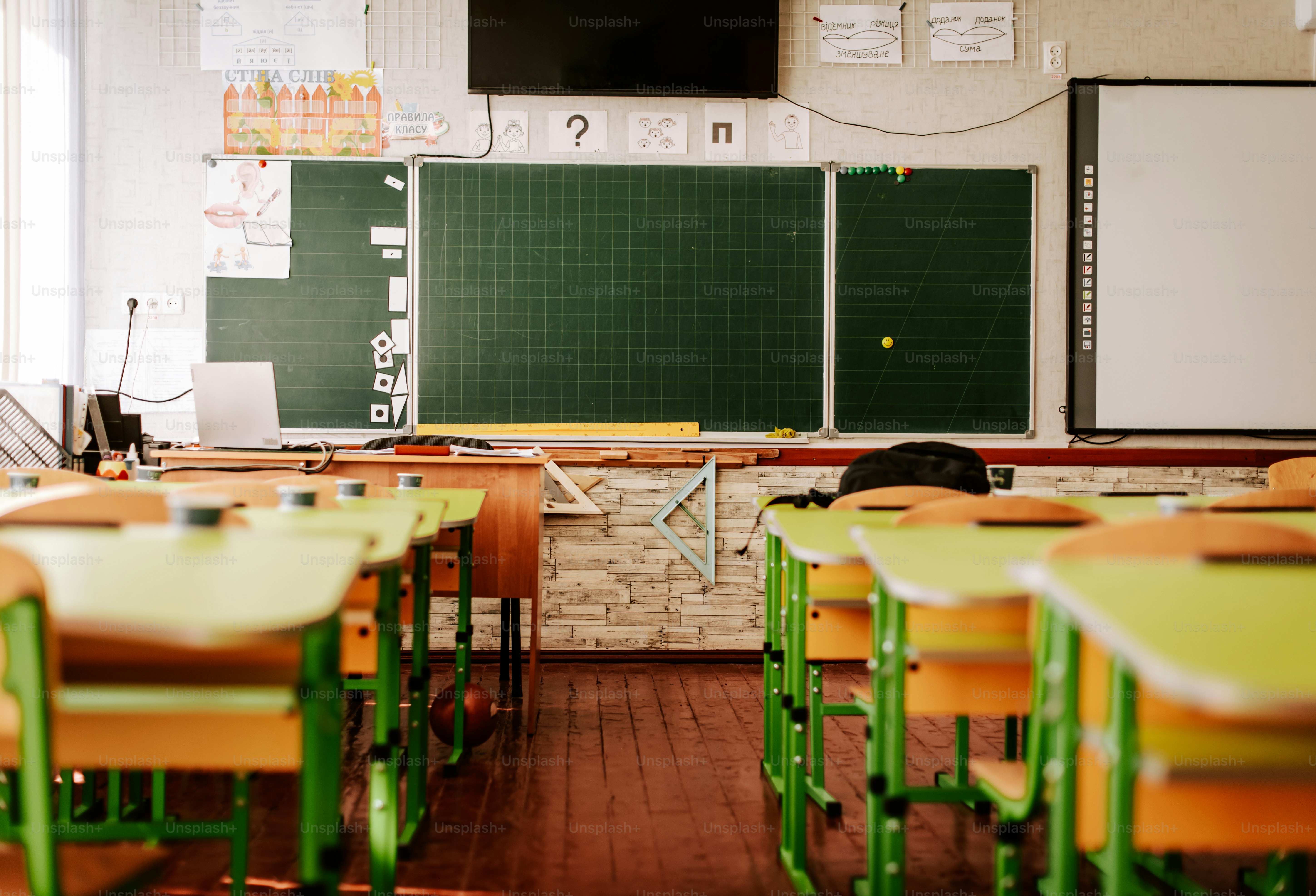 A classroom with desks and a television on the wall