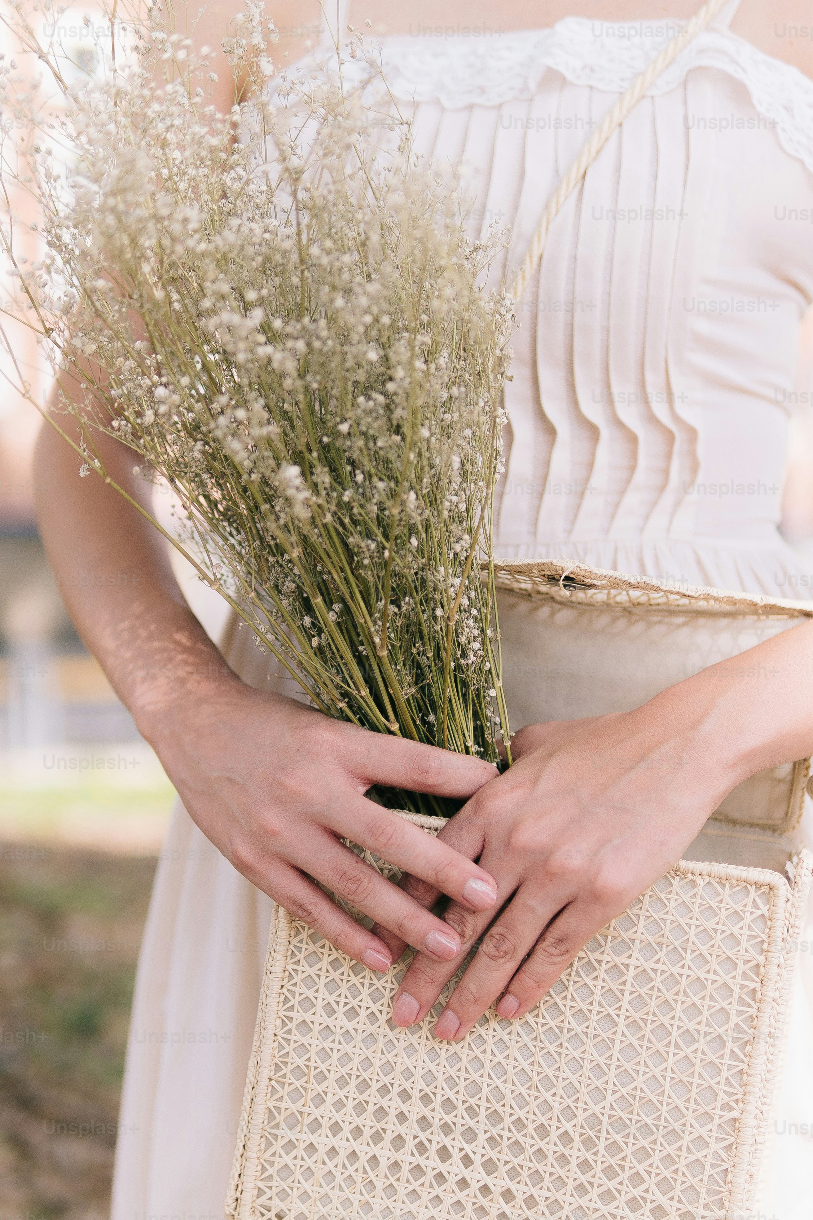 Une femme en robe blanche tenant un bouquet de fleurs