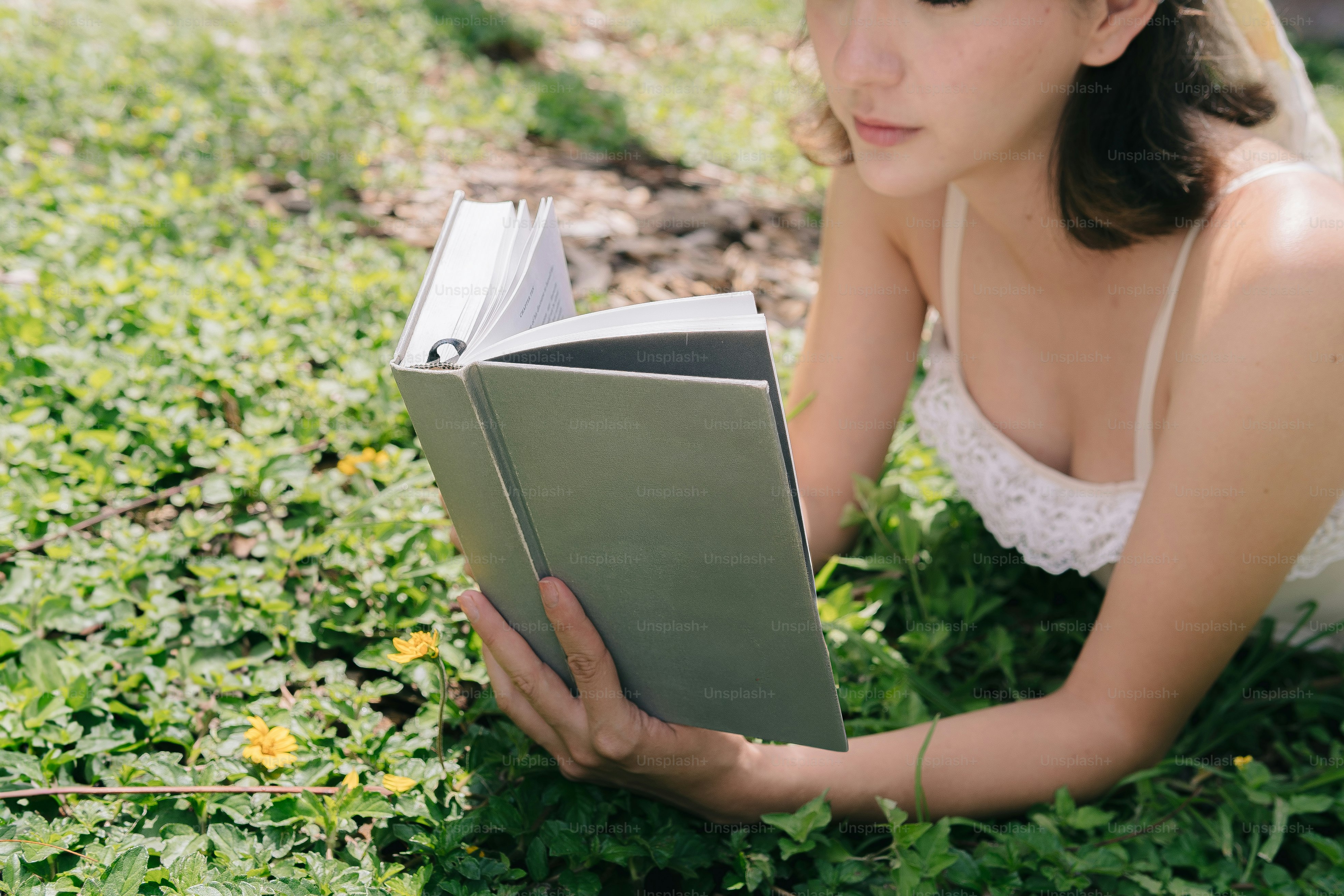 Une femme lit un livre dans l’herbe