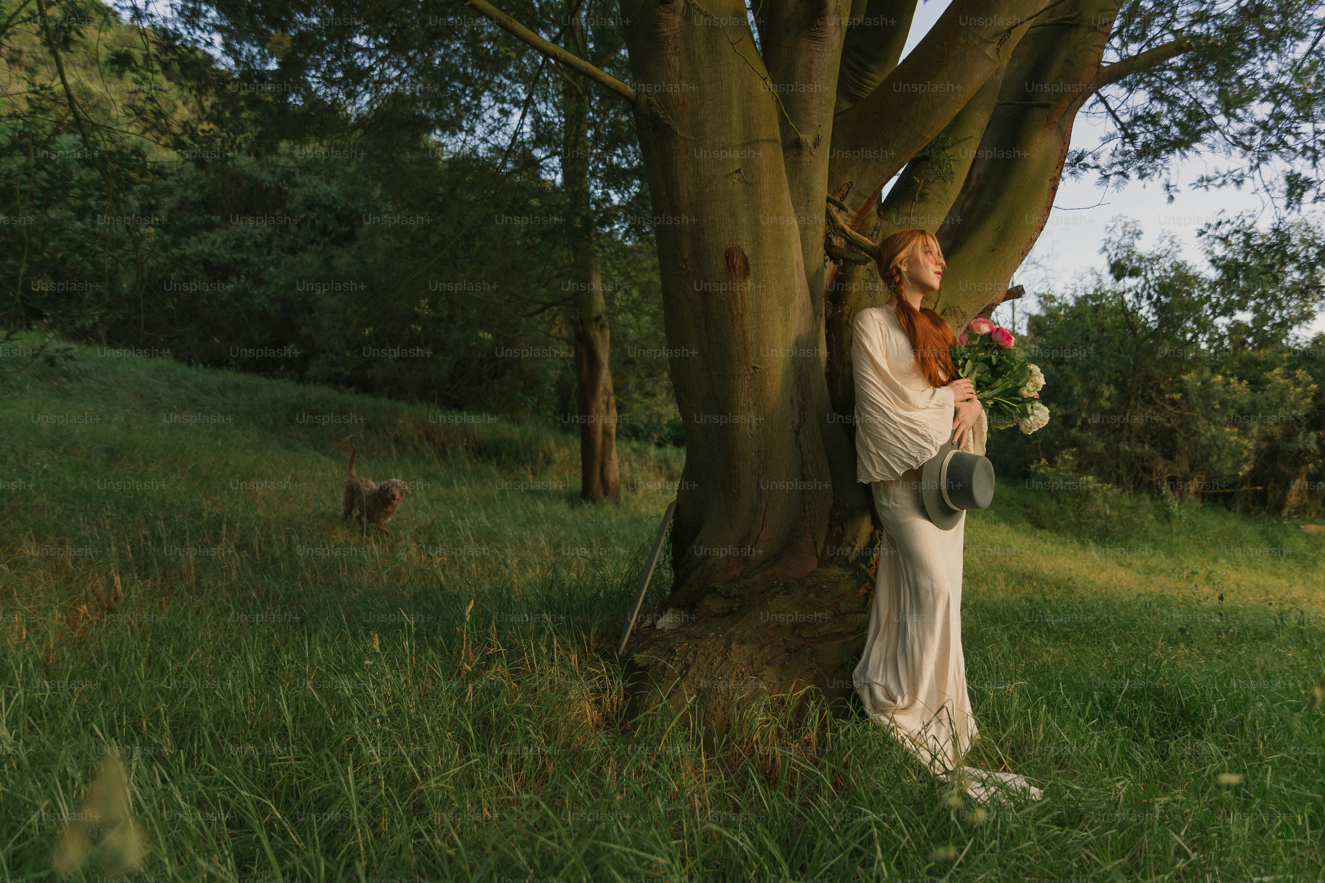 木のそばに立つ白いドレスの女性
