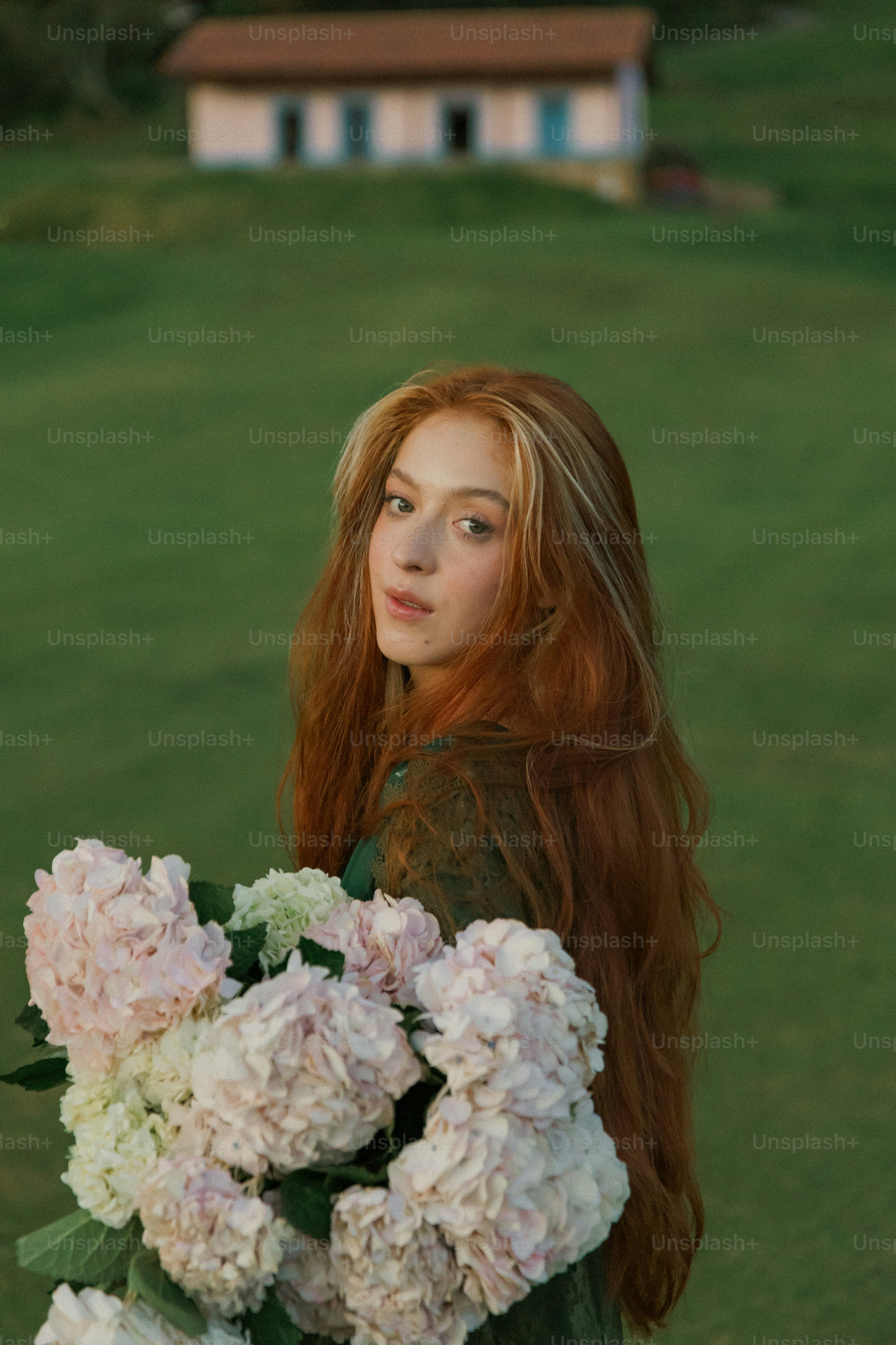 A woman with long red hair holding a bouquet of flowers