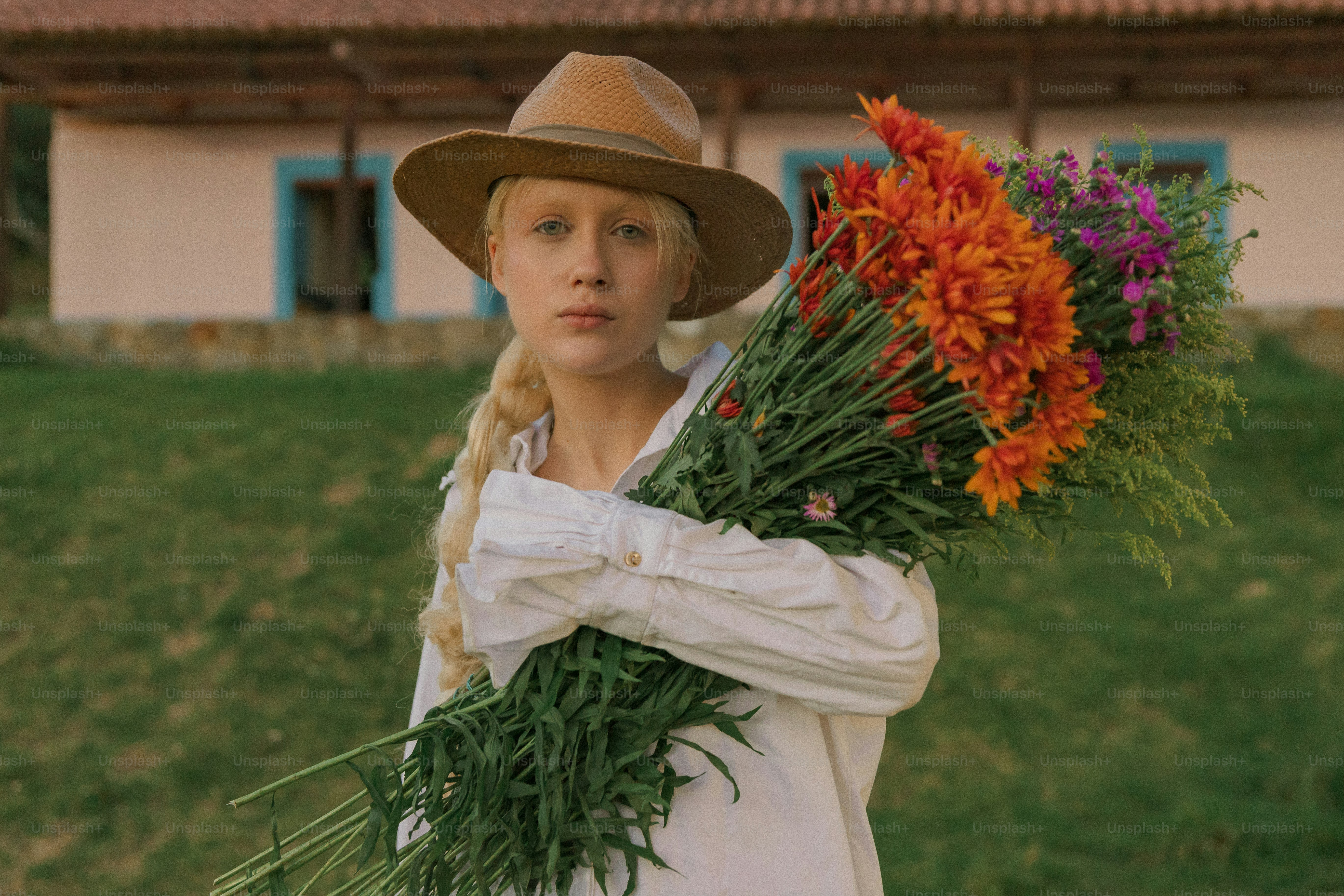 Une femme avec un chapeau tenant un bouquet de fleurs