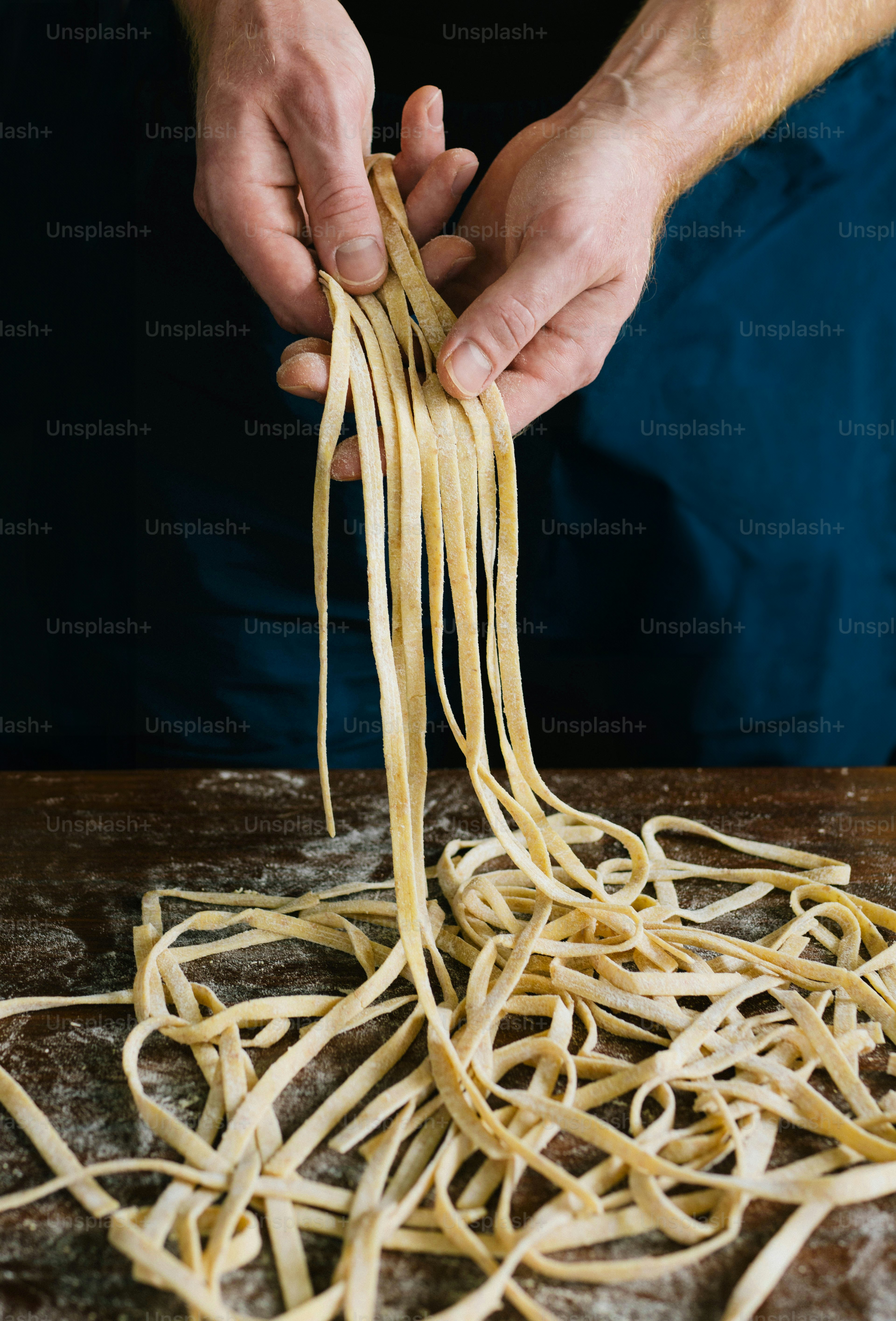 Una persona sosteniendo un tenedor sobre una pila de fideos