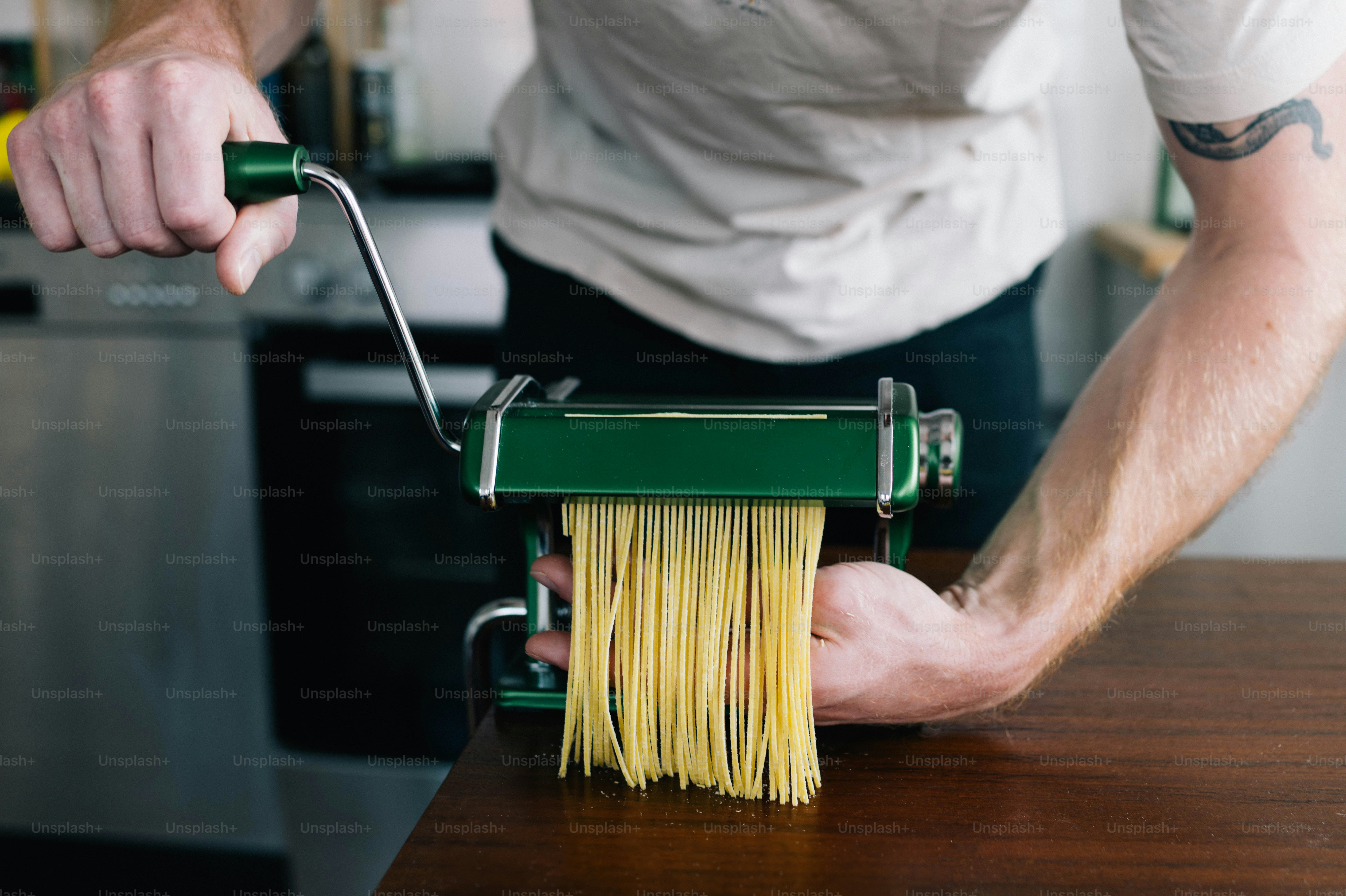 Un hombre sosteniendo un rodillo de pasta verde y amarillo