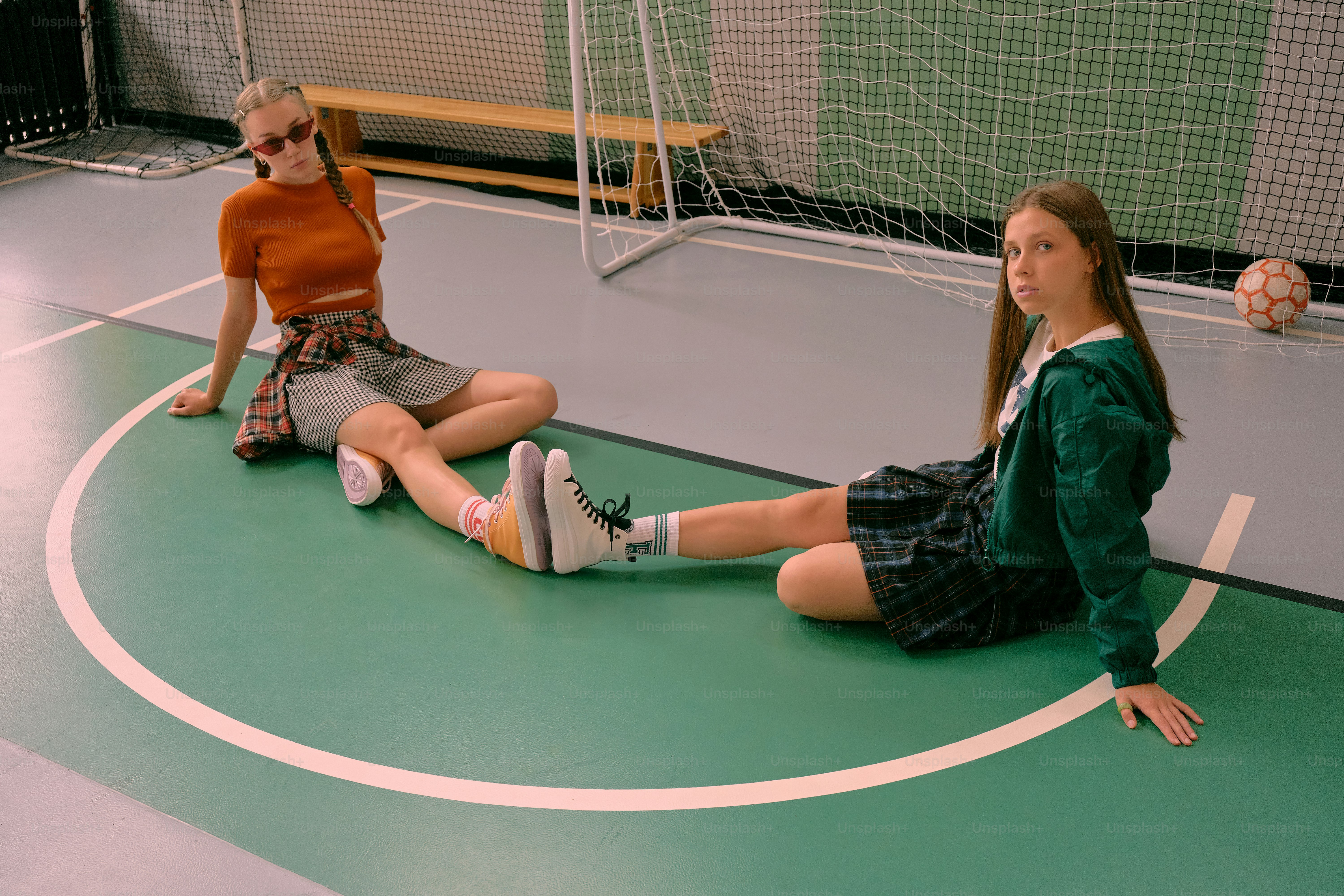 Two young girls sitting on a basketball court