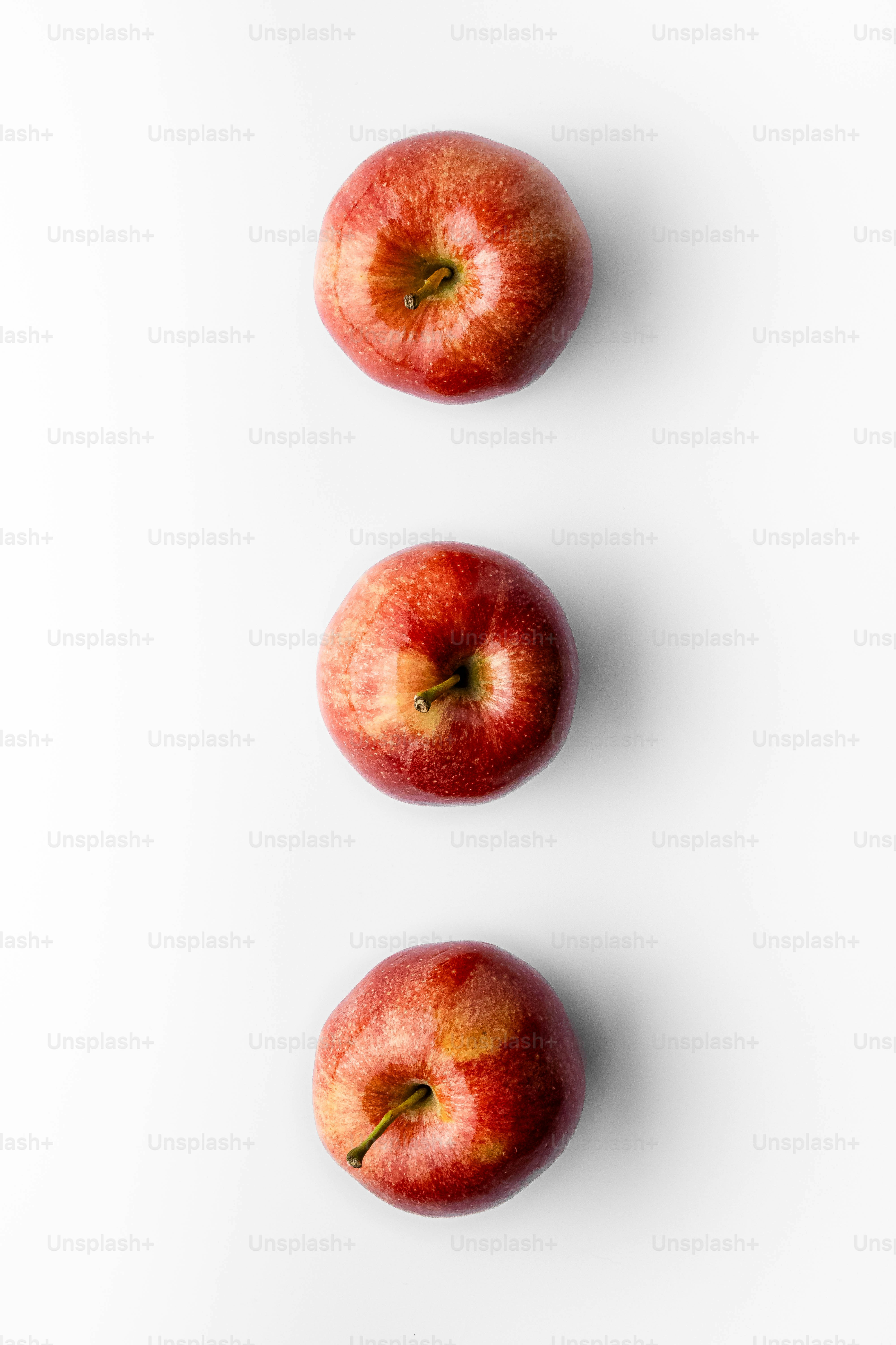 Three apples sitting in a row on a white surface