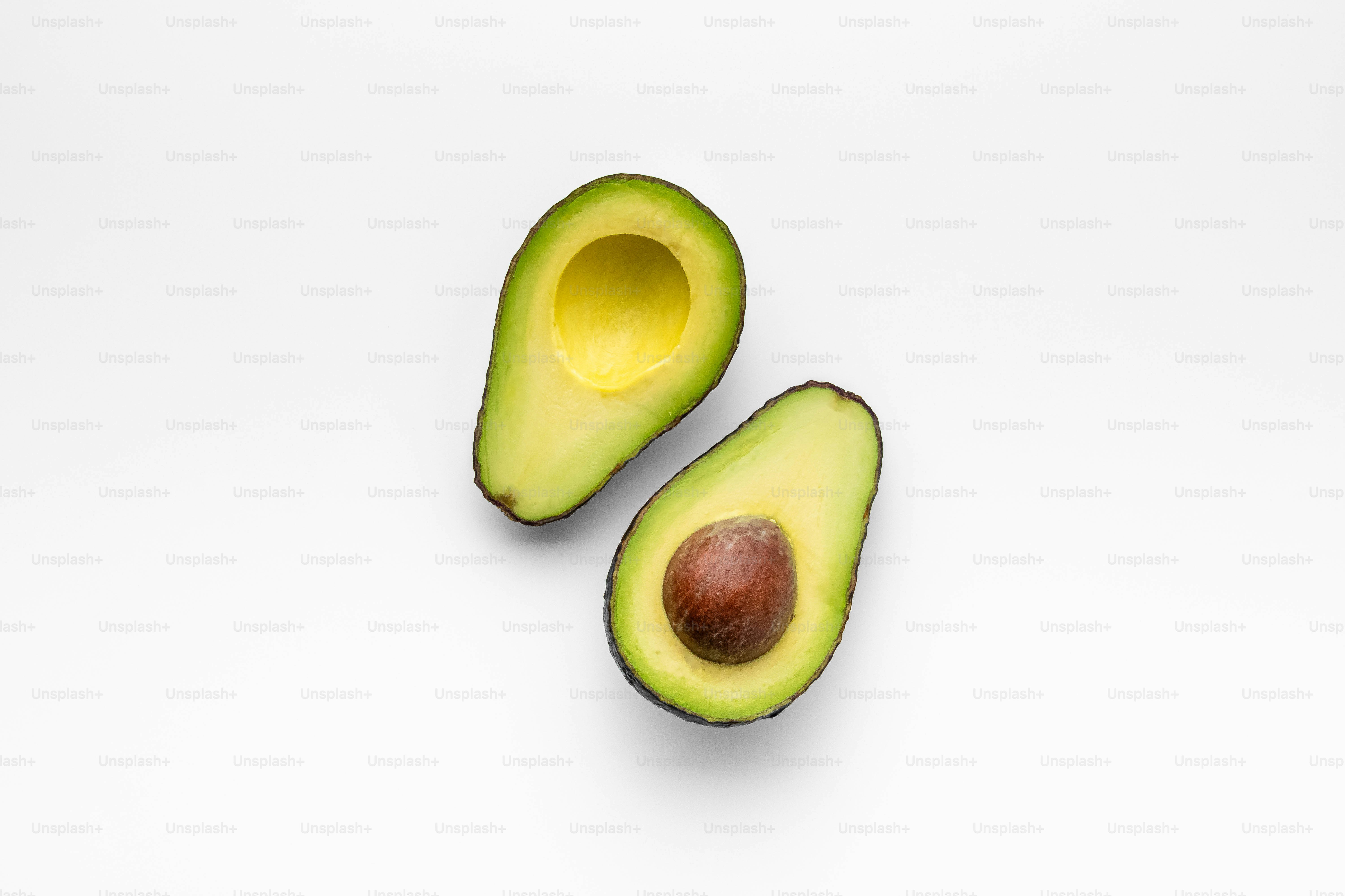 An avocado cut in half on a white surface