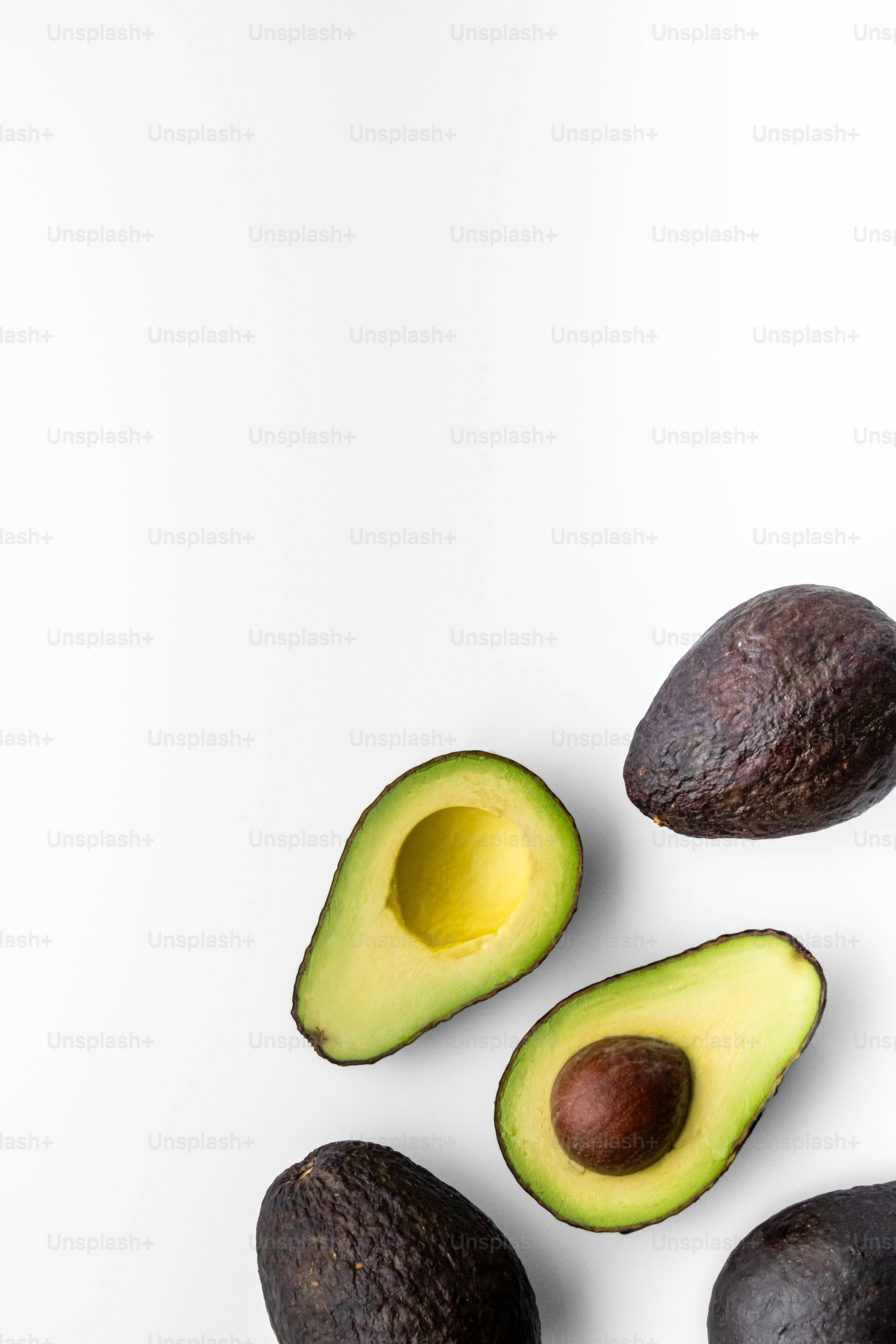 Un aguacate cortado por la mitad sobre una superficie blanca