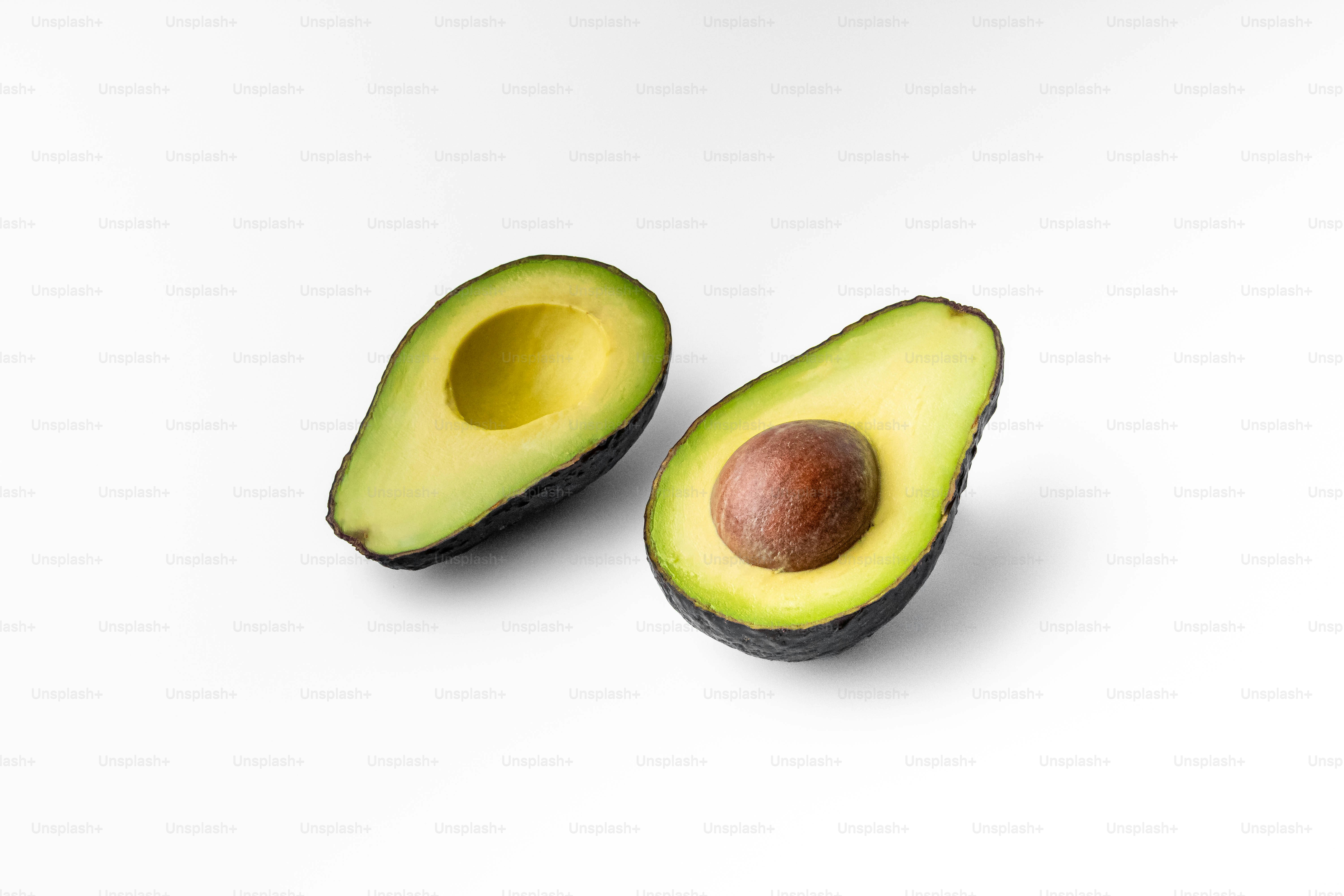An avocado cut in half on a white surface