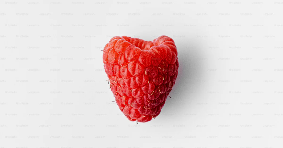 A raspberry in the shape of a heart on a white background photo – Food ...