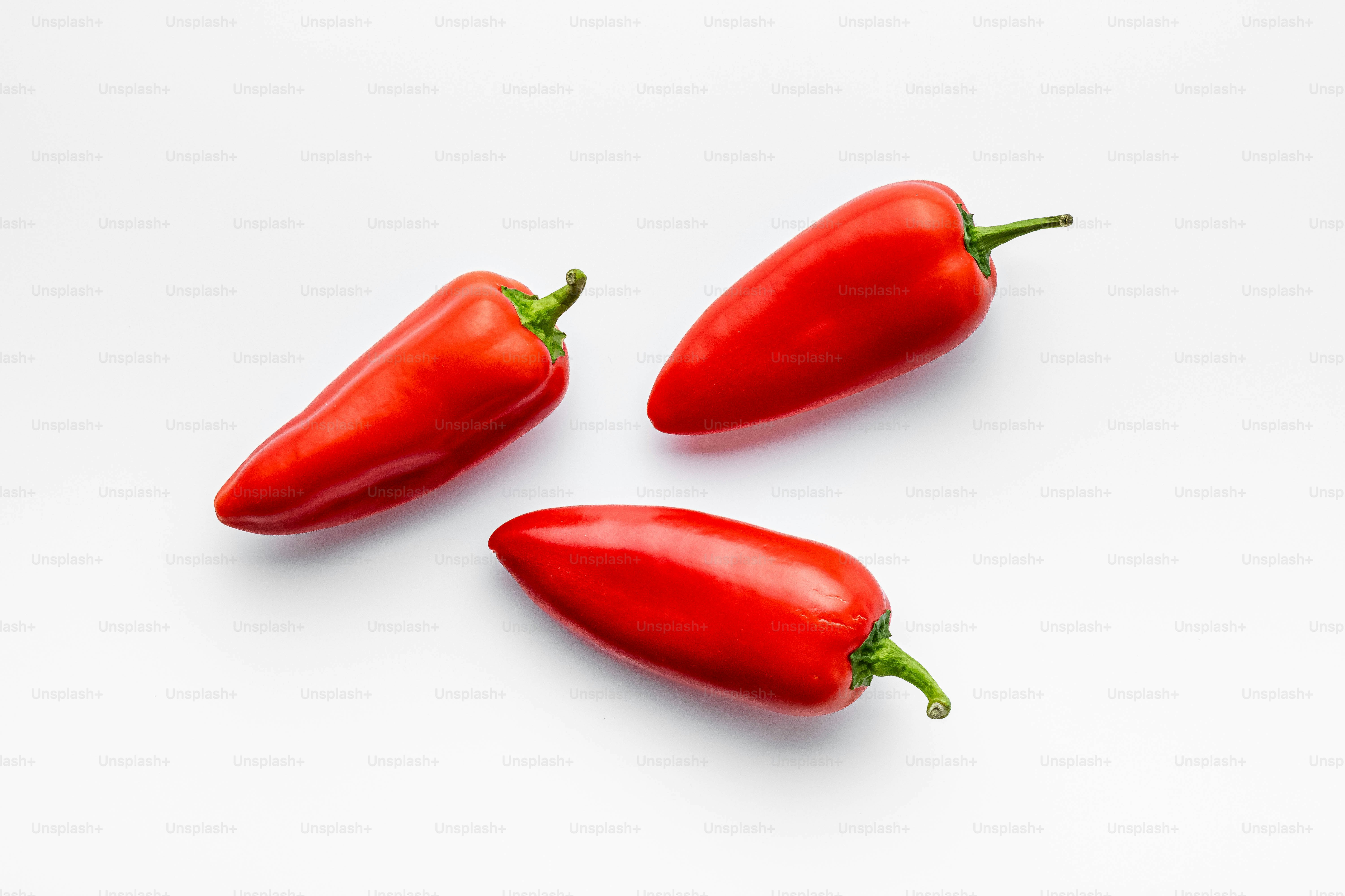 Three red hot peppers on a white background