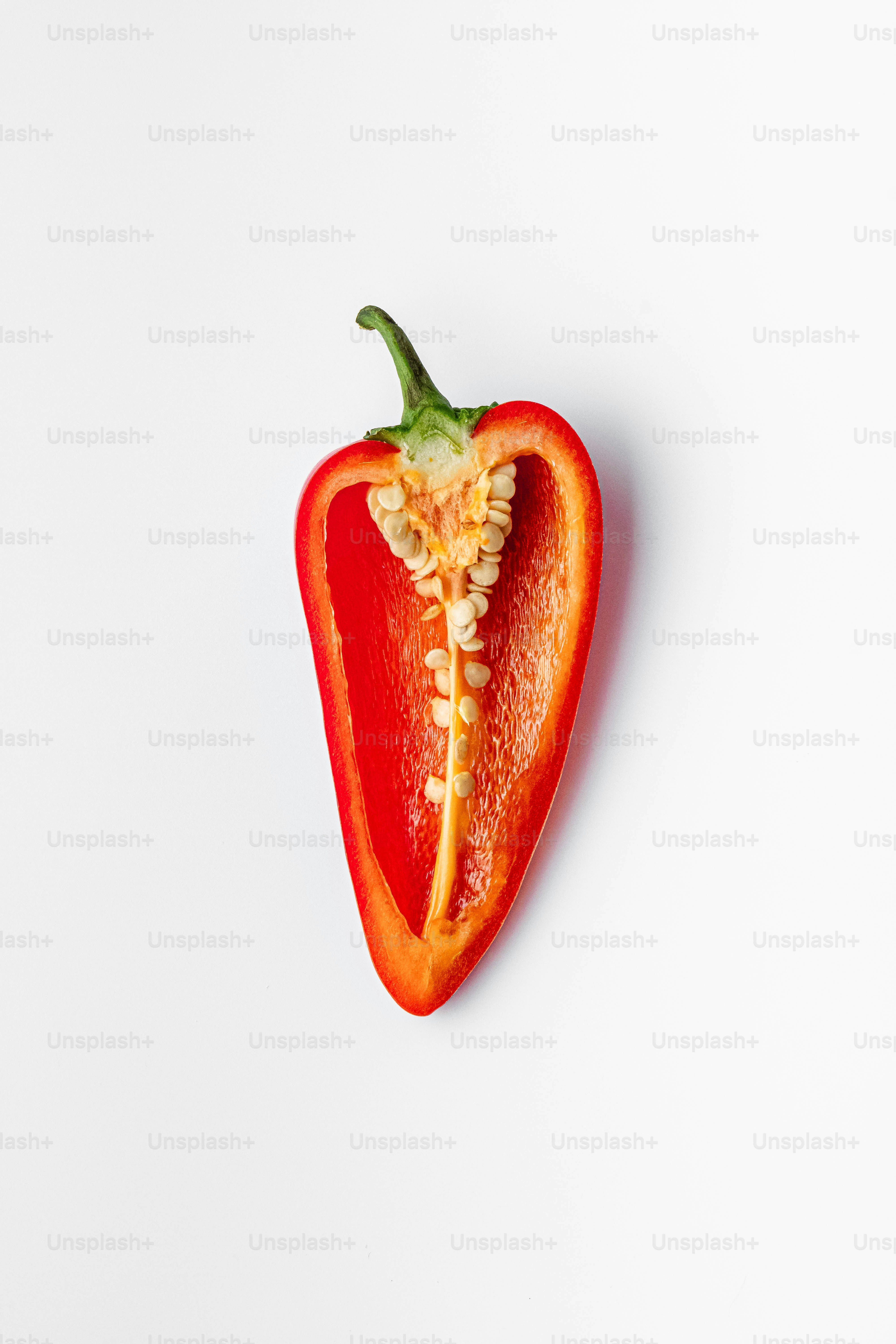 Un peperone rosso mangiato a metà su una superficie bianca