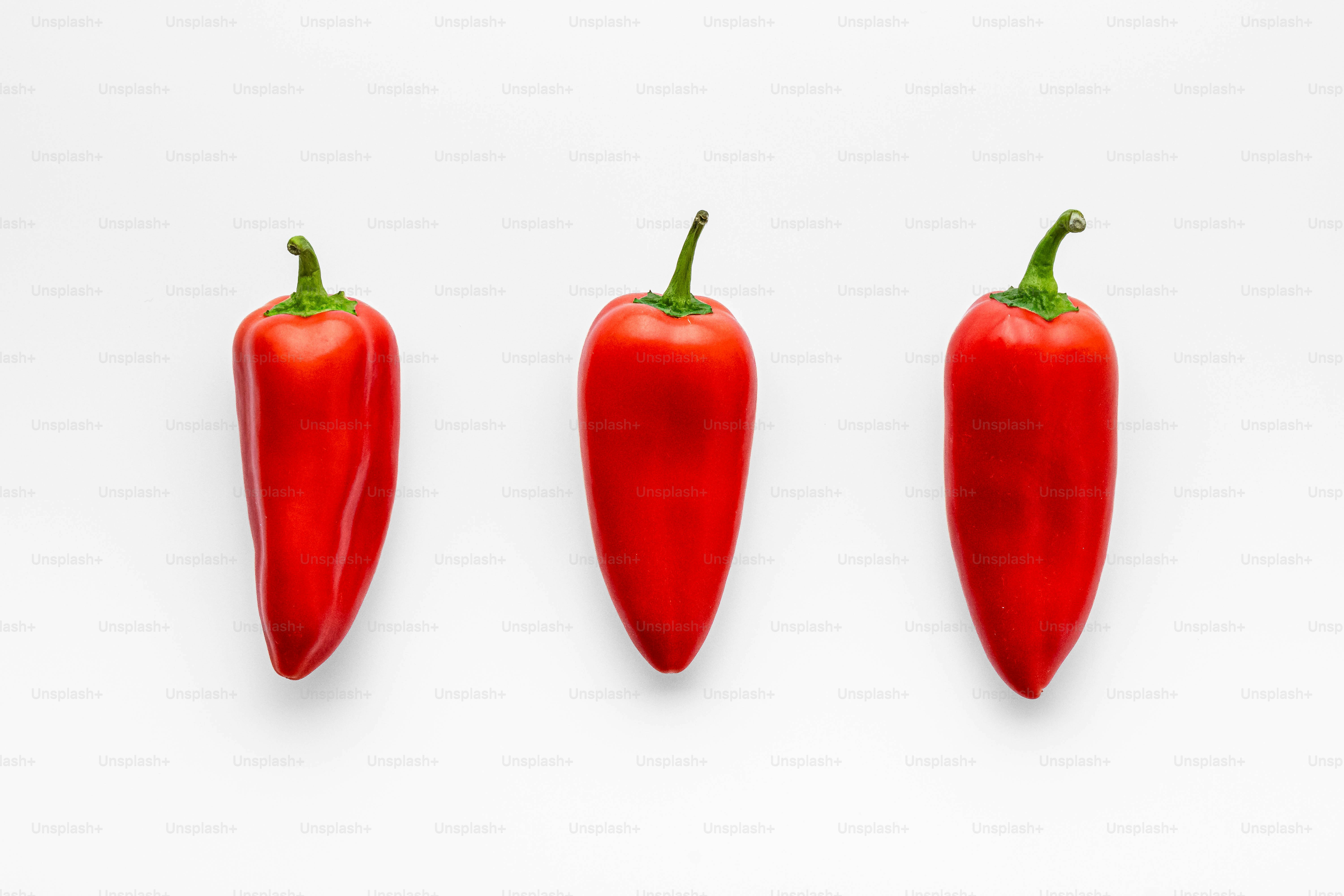 A group of three red peppers sitting next to each other