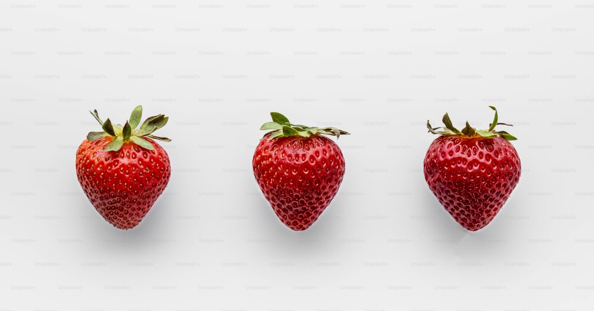 Four strawberries lined up in a row on a white background photo ...