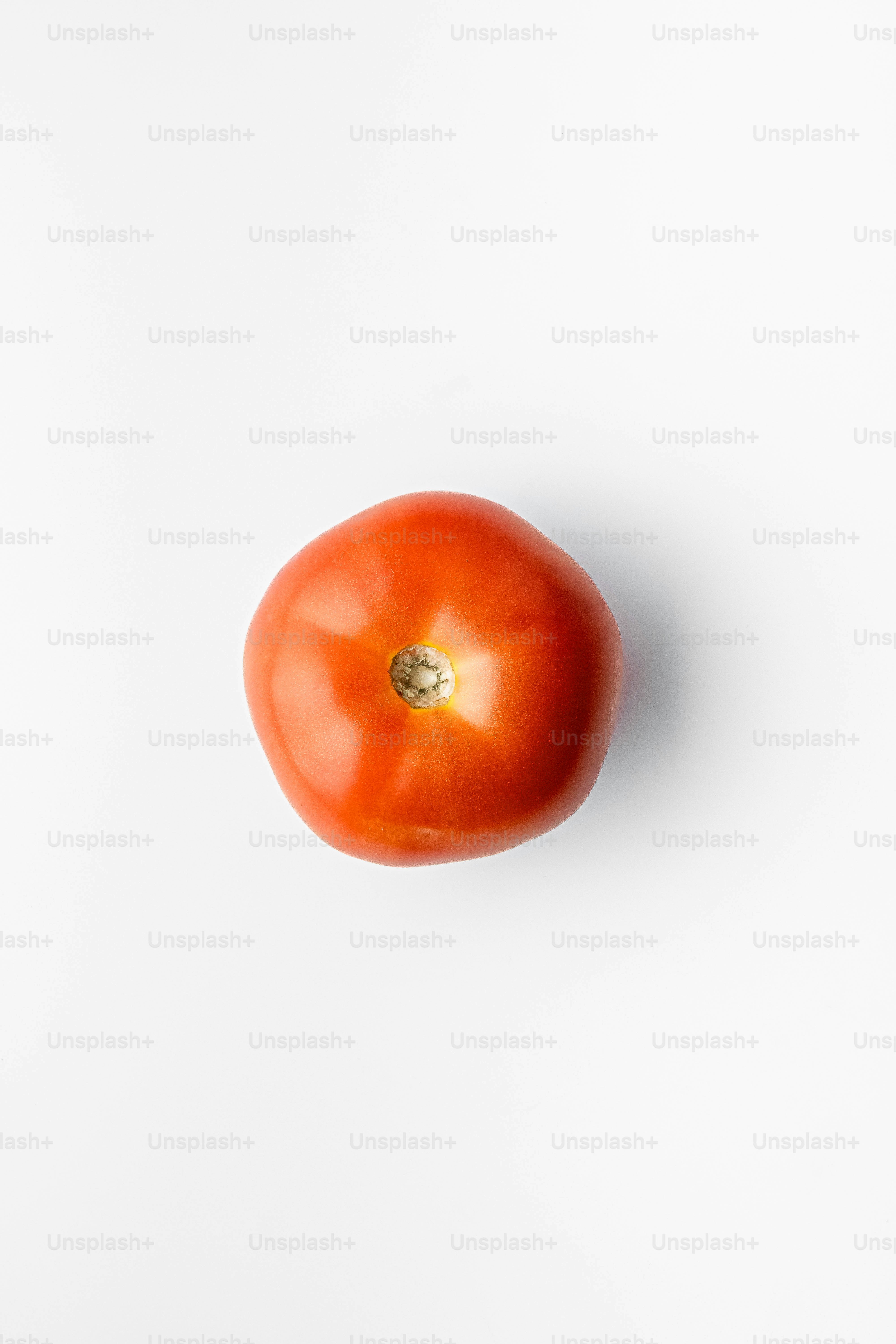 A single tomato on a white surface