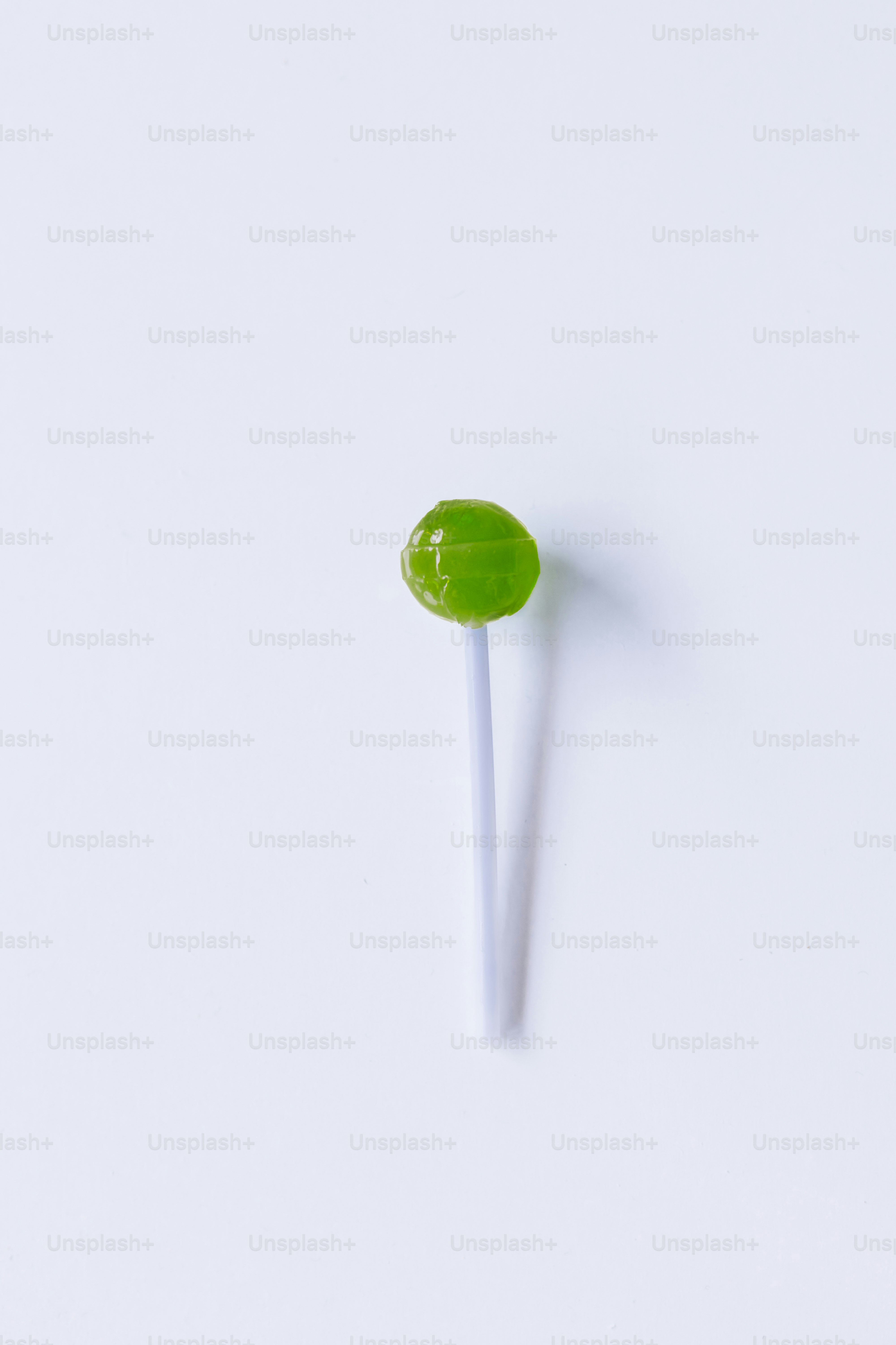 A green lollipop sitting on top of a white table