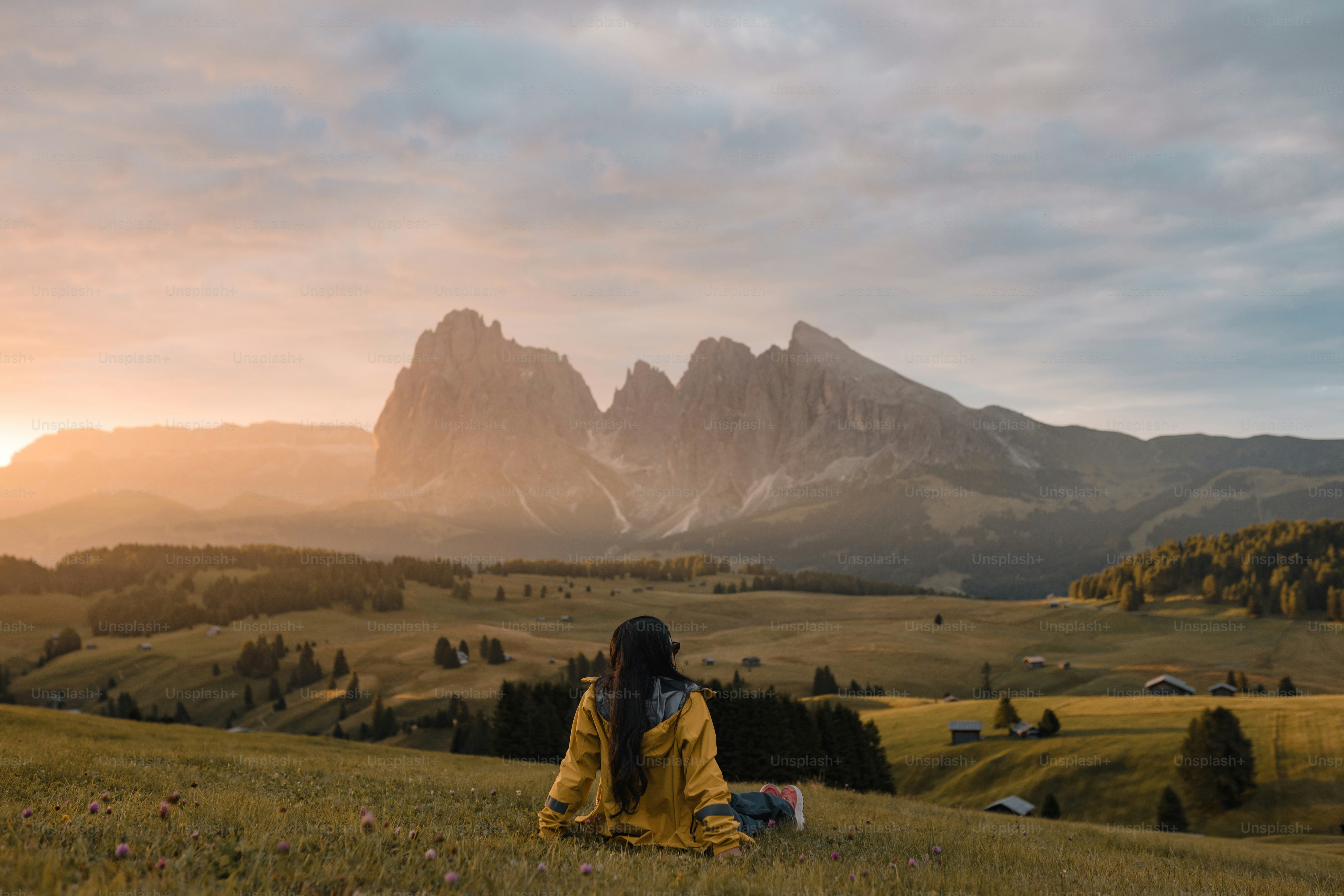 Une personne assise dans un champ avec des montagnes en arrière-plan