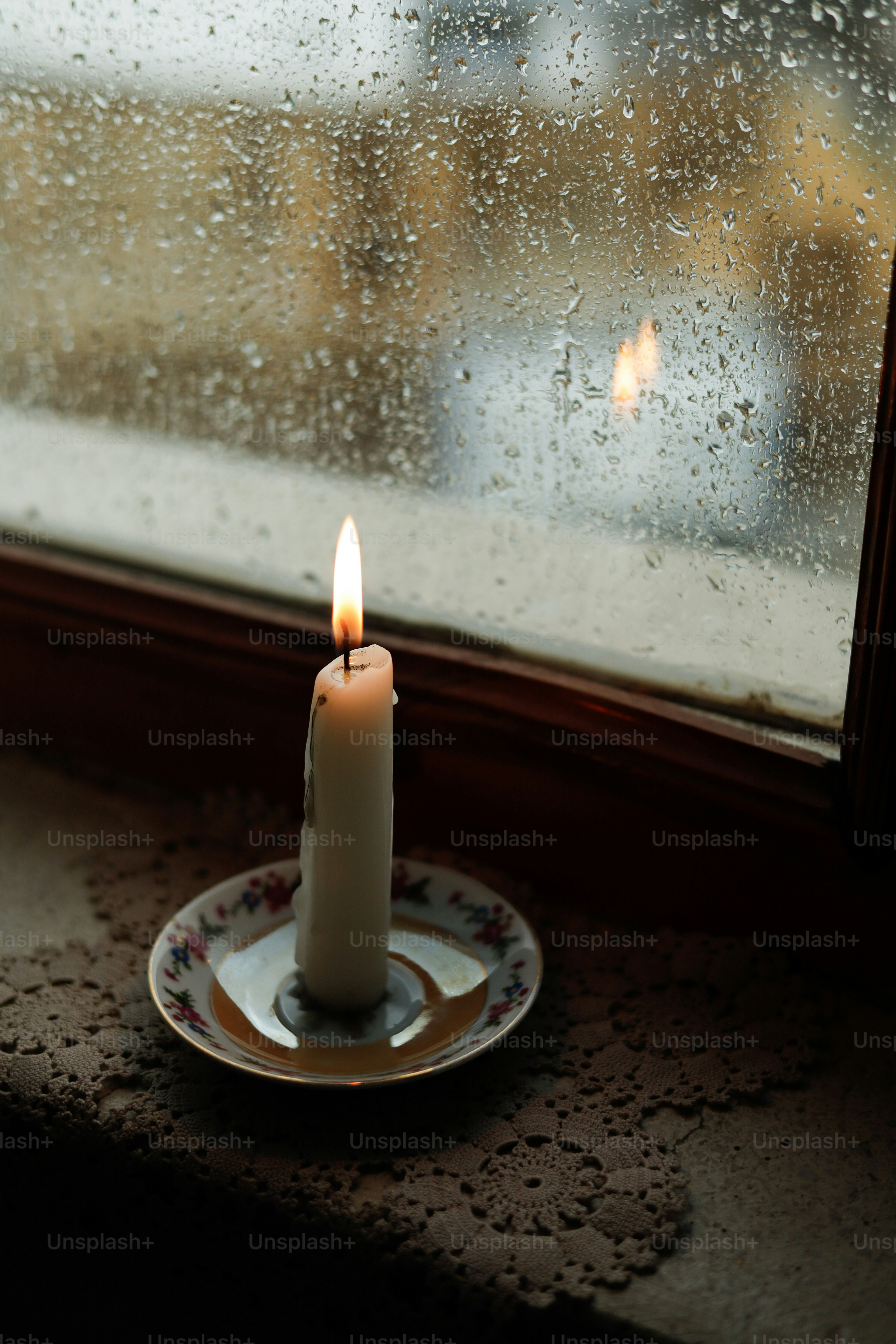 A candle sitting on a plate in front of a window