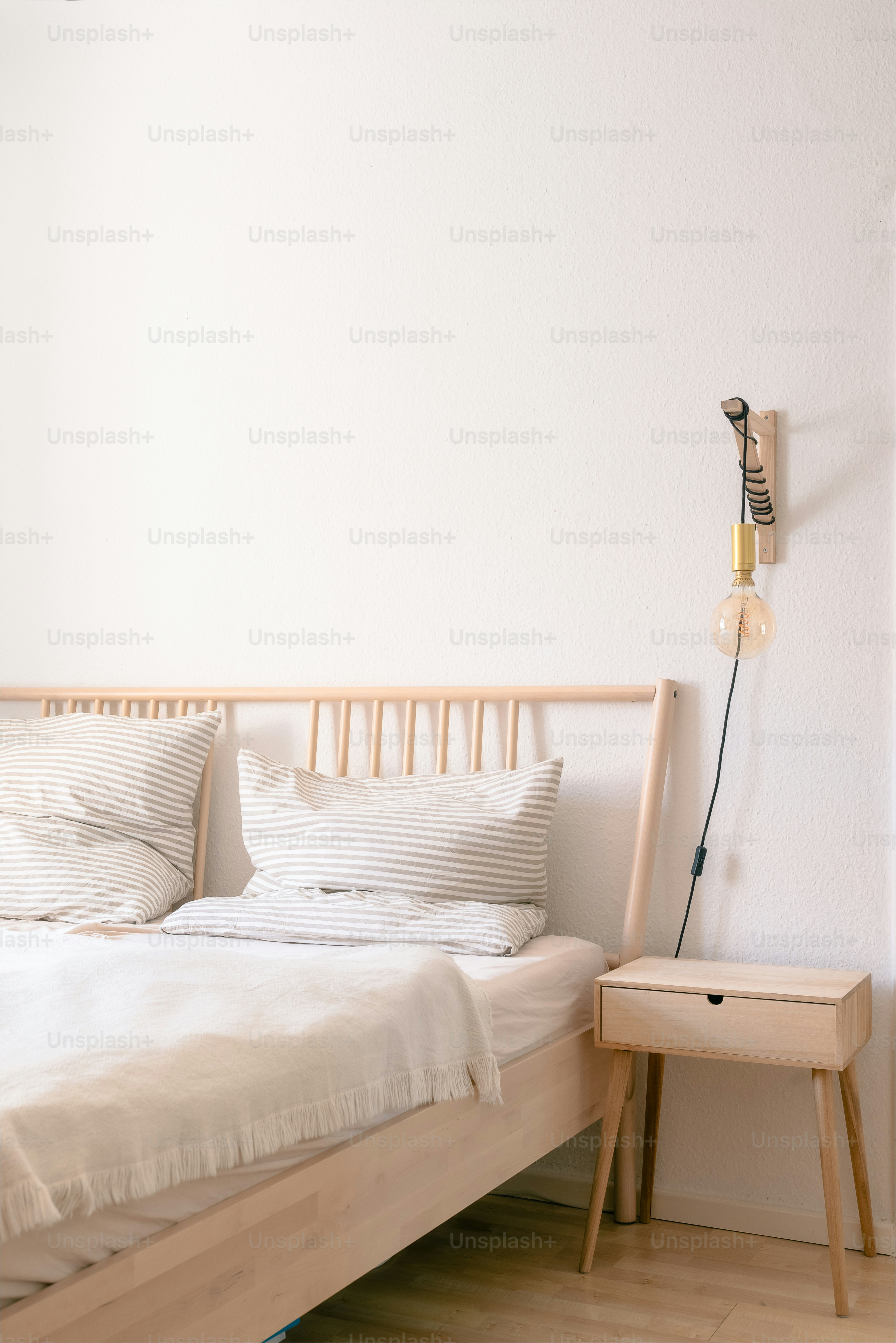A bed with white sheets and pillows in a room