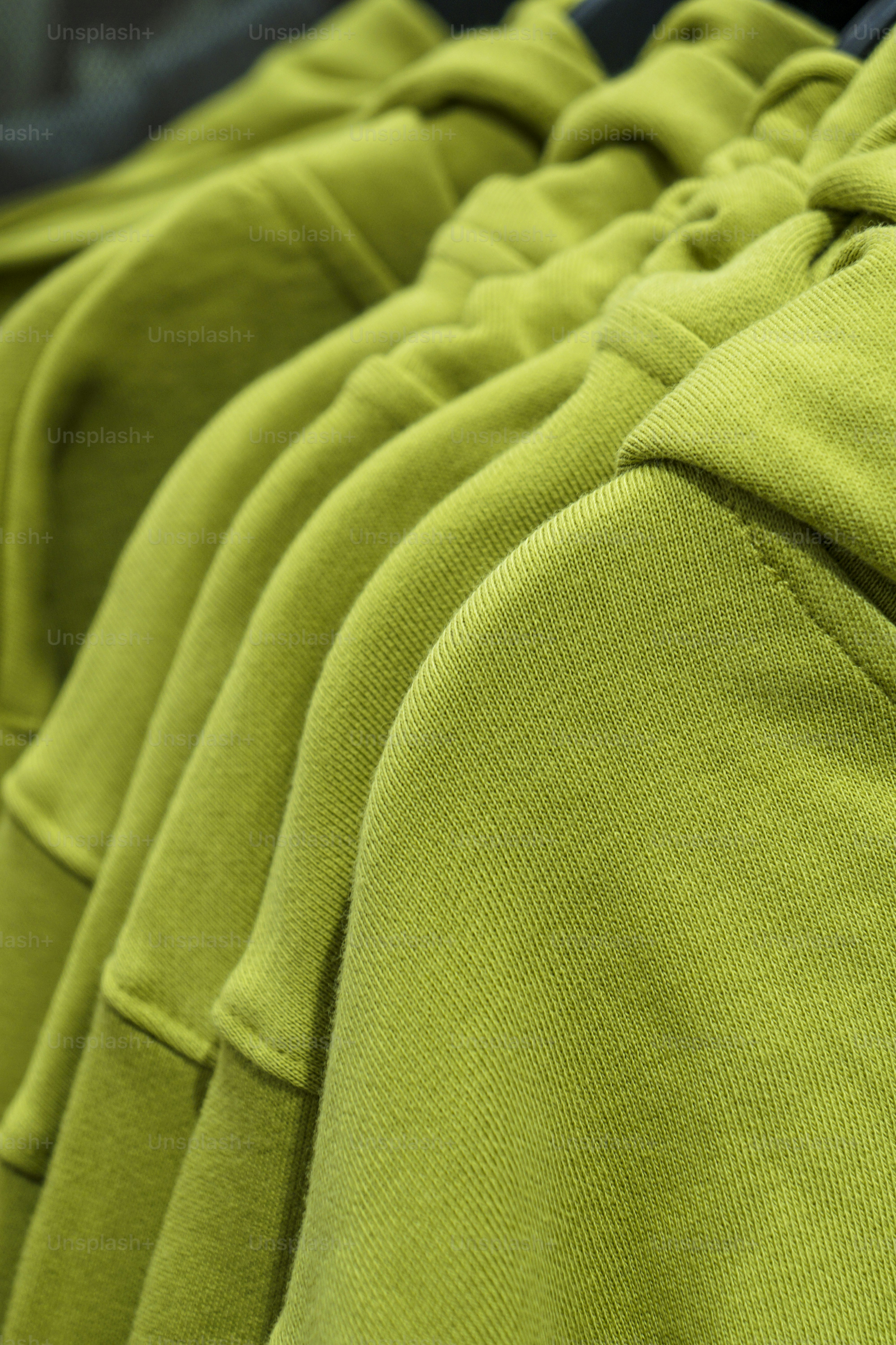 A row of green sweatshirts hanging on a rack
