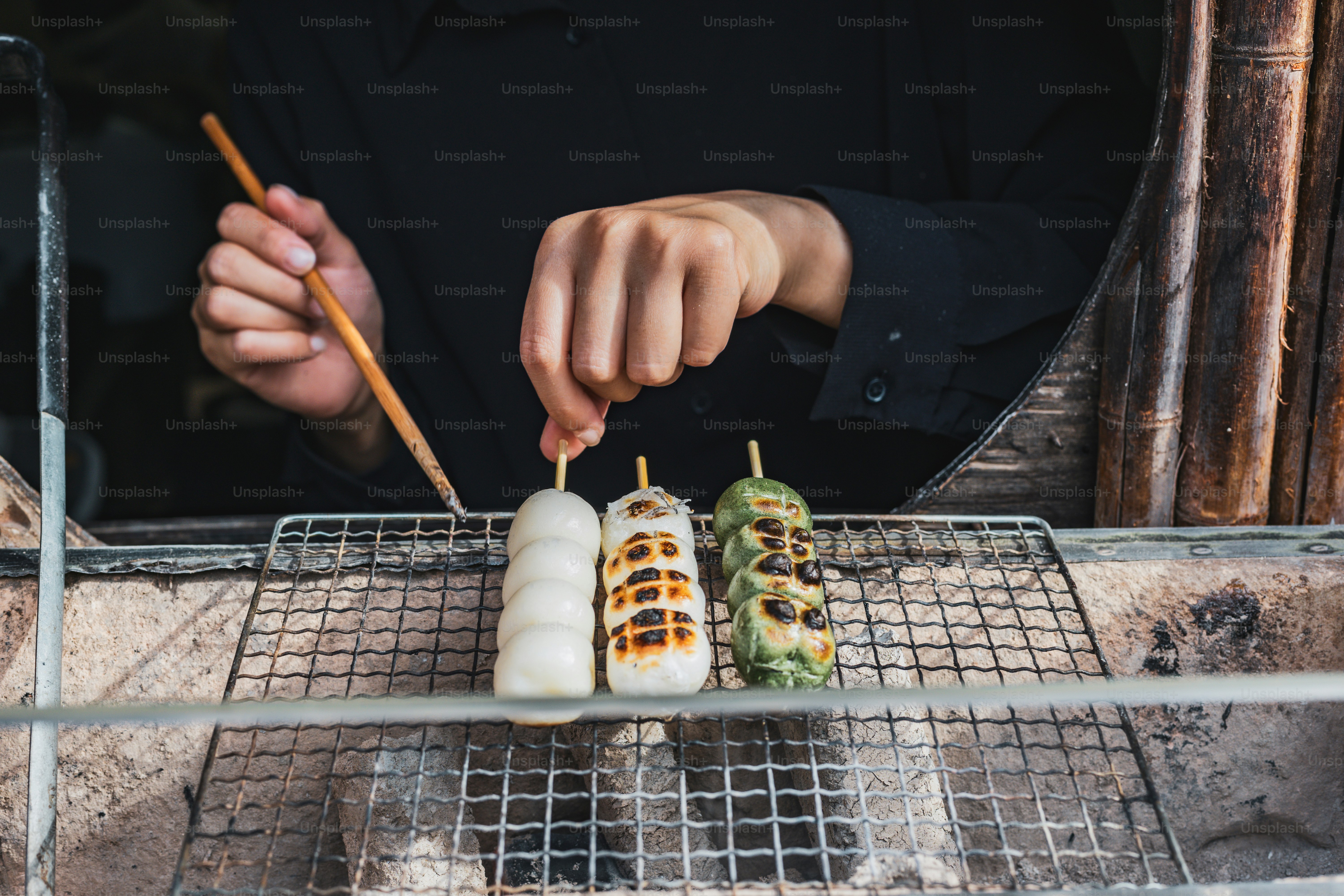 A man preparing food on a grill with chopsticks