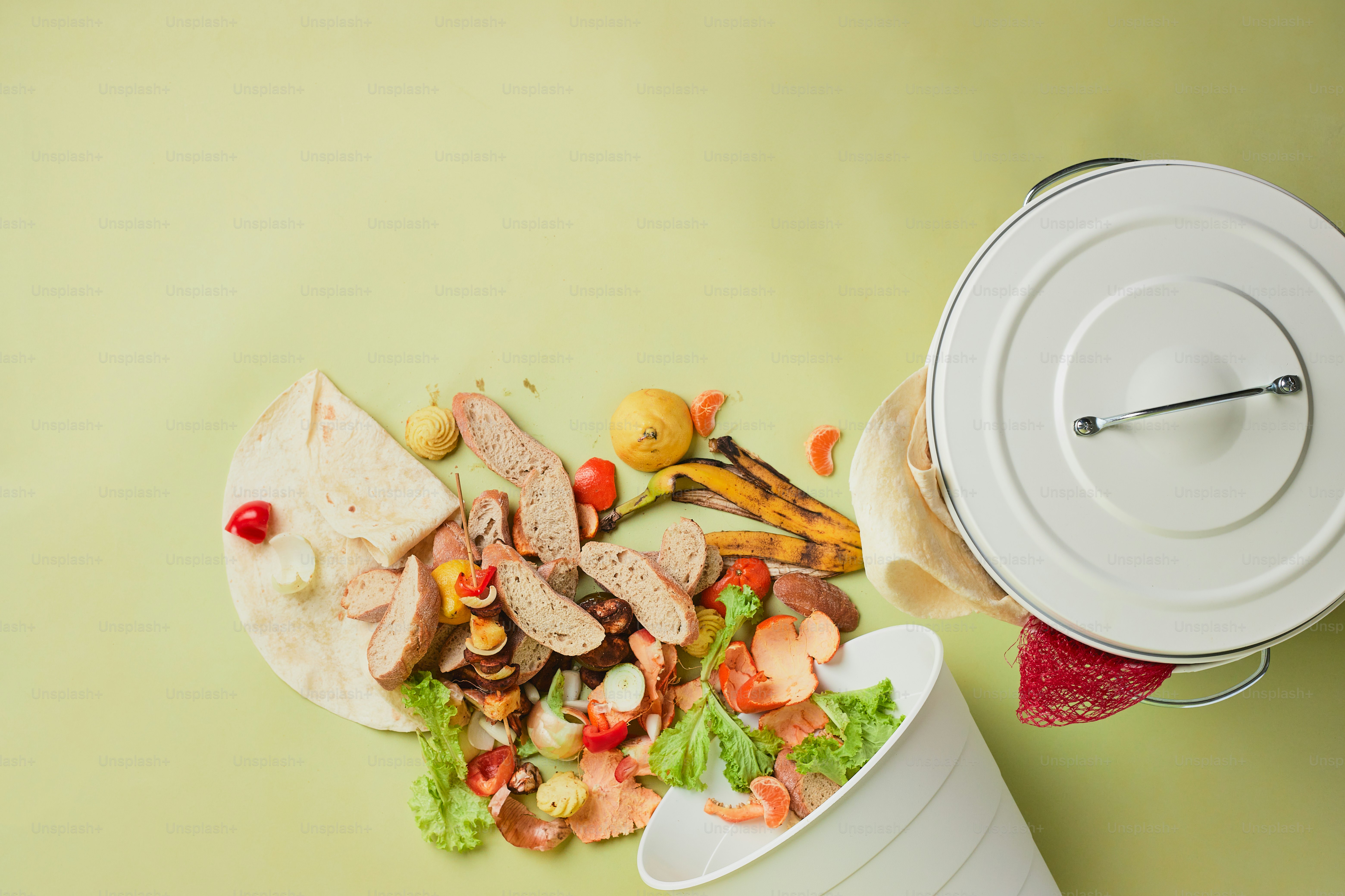 A trash can with food in it next to a trash can