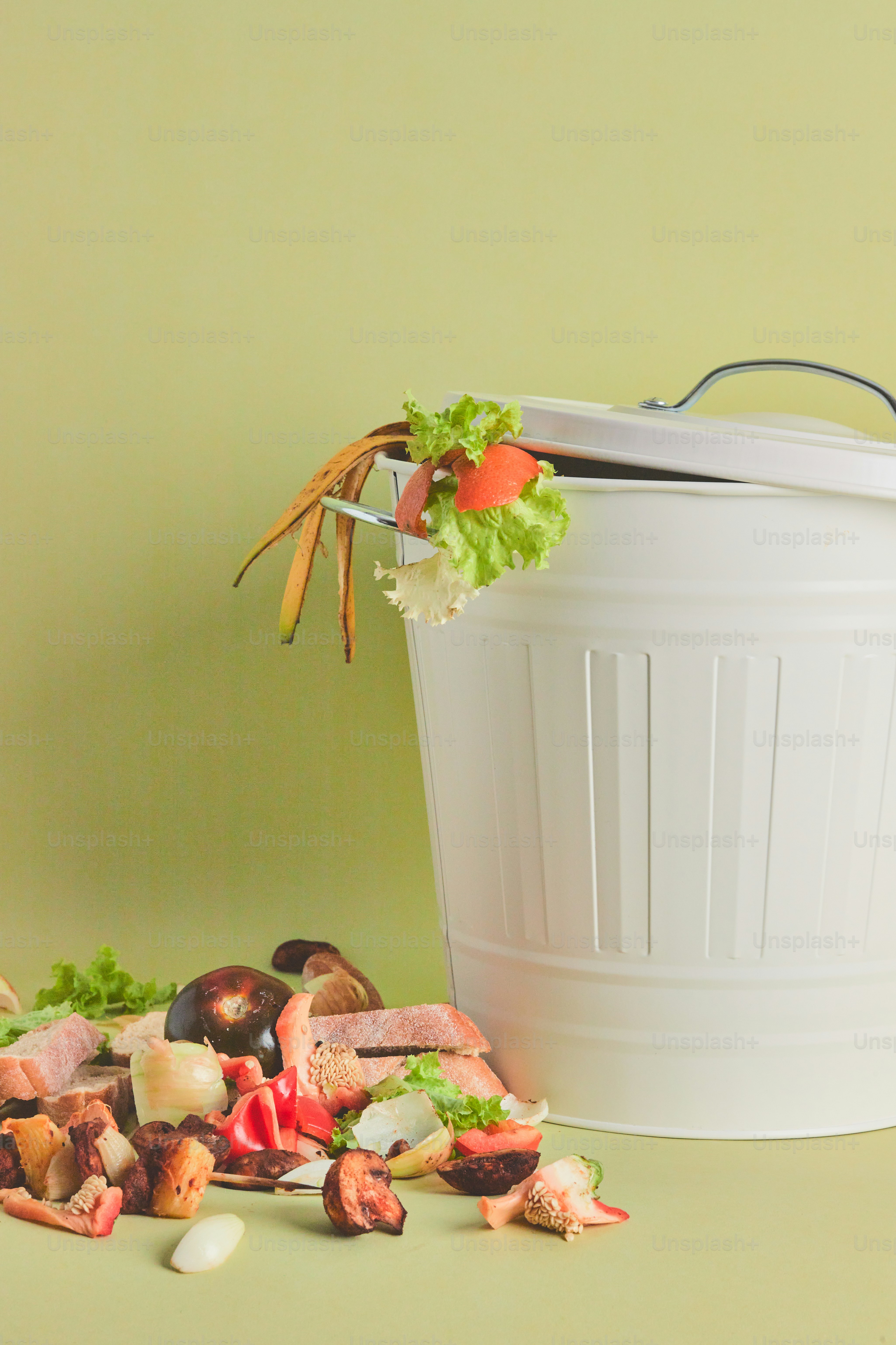 A white trash can sitting next to a pile of food