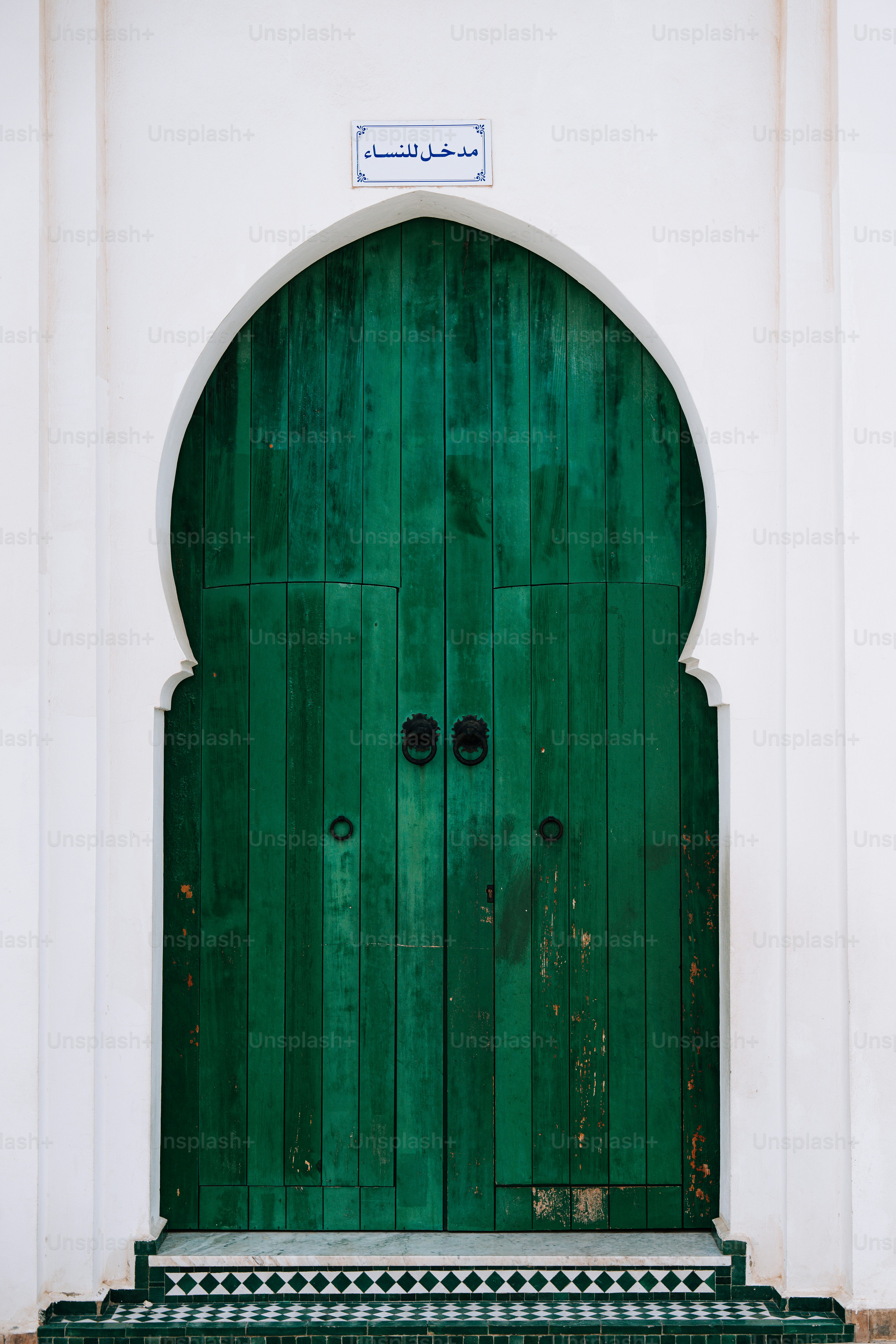 A green door with a bench in front of it