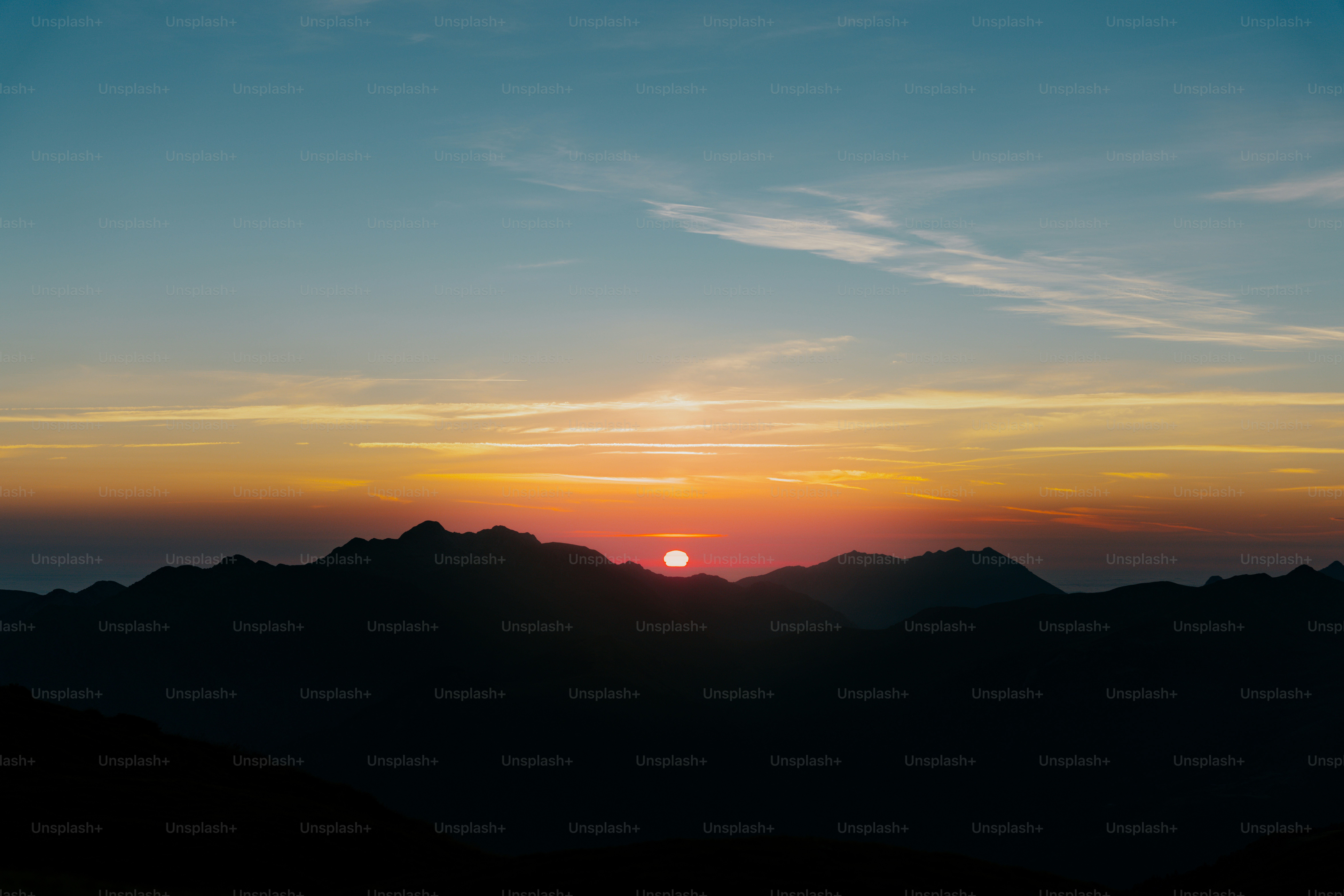 The sun is setting over a mountain range