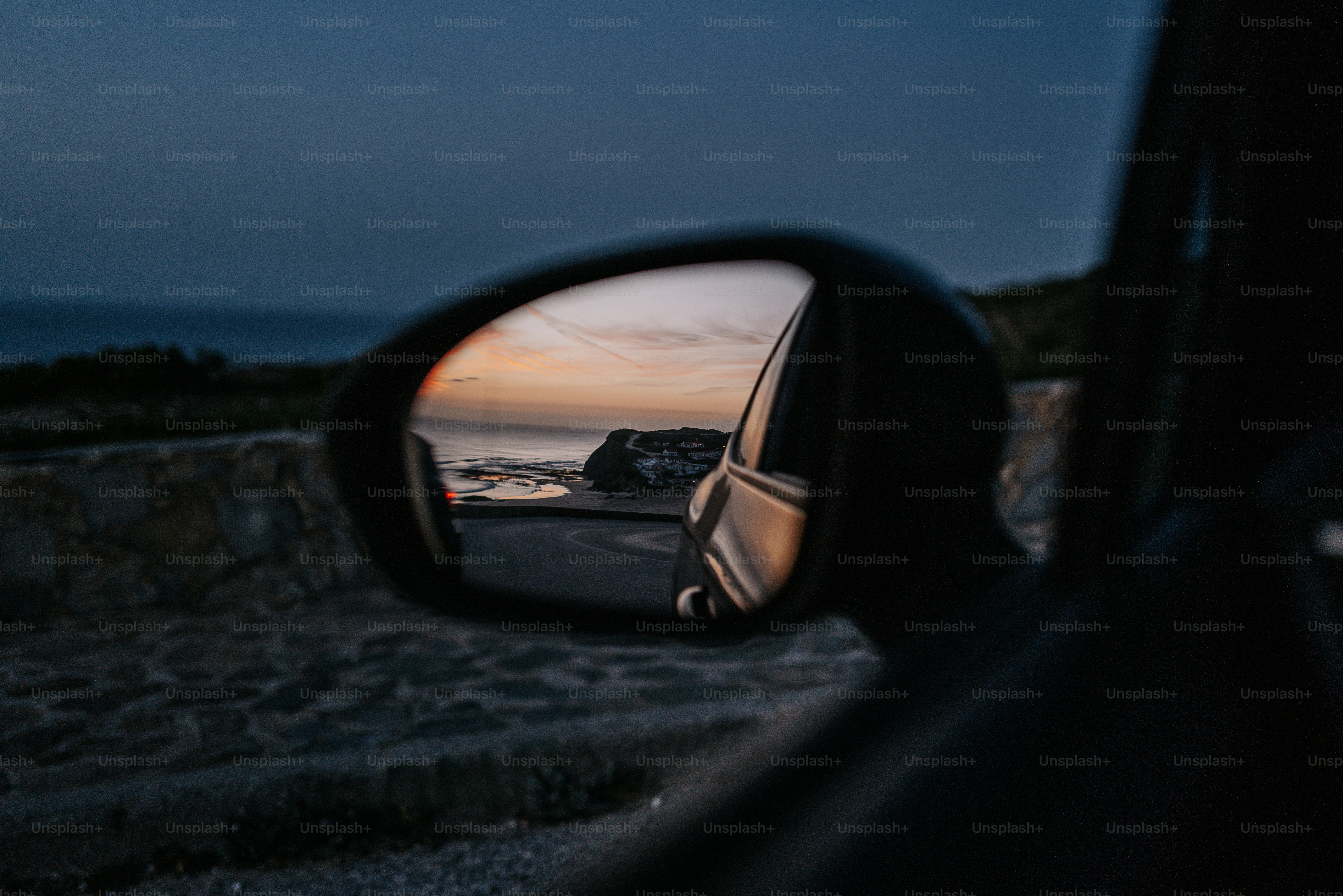 A car's side view mirror reflecting the ocean