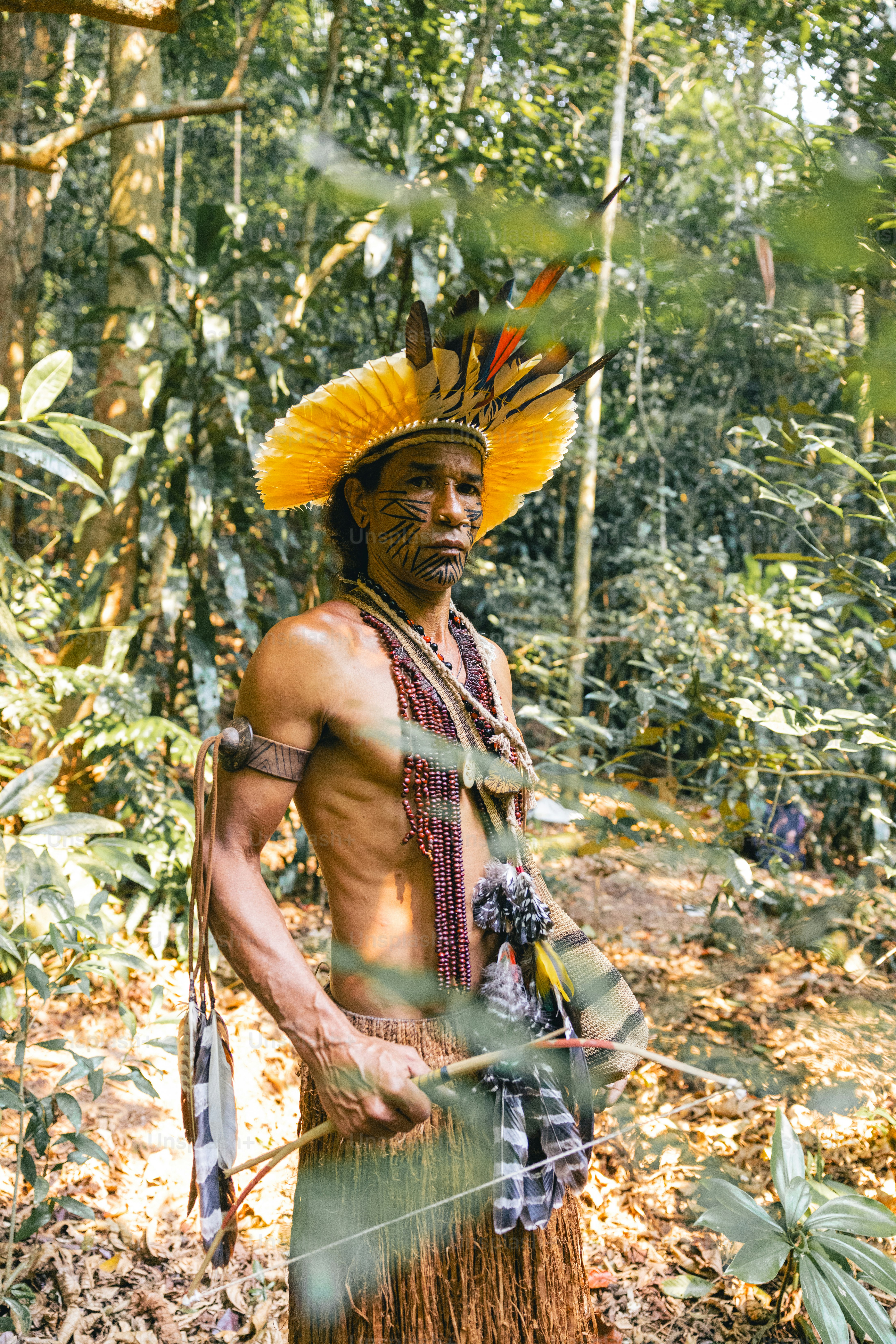A man with a yellow hat standing in the woods