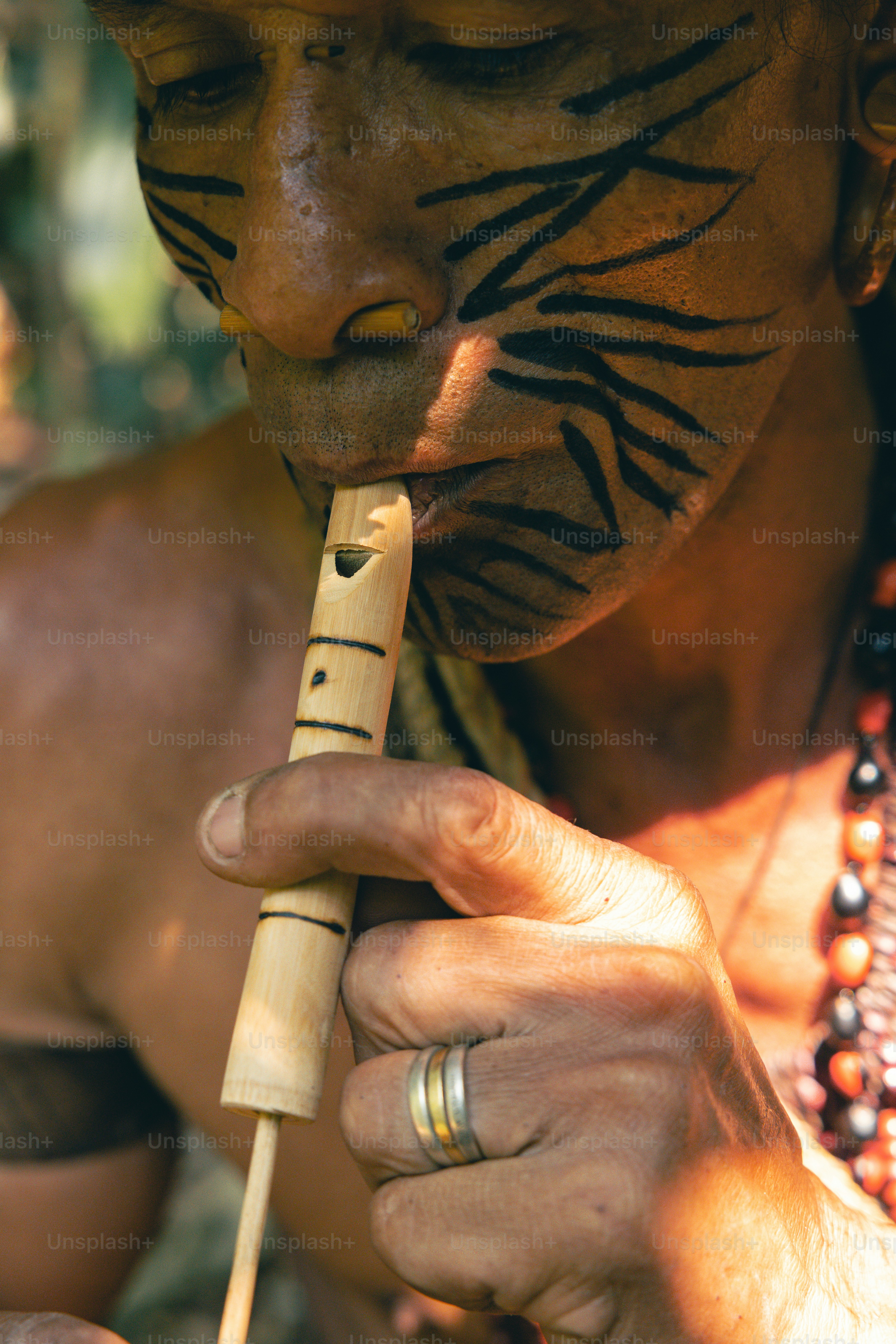 A man with a tiger painted face playing a flute