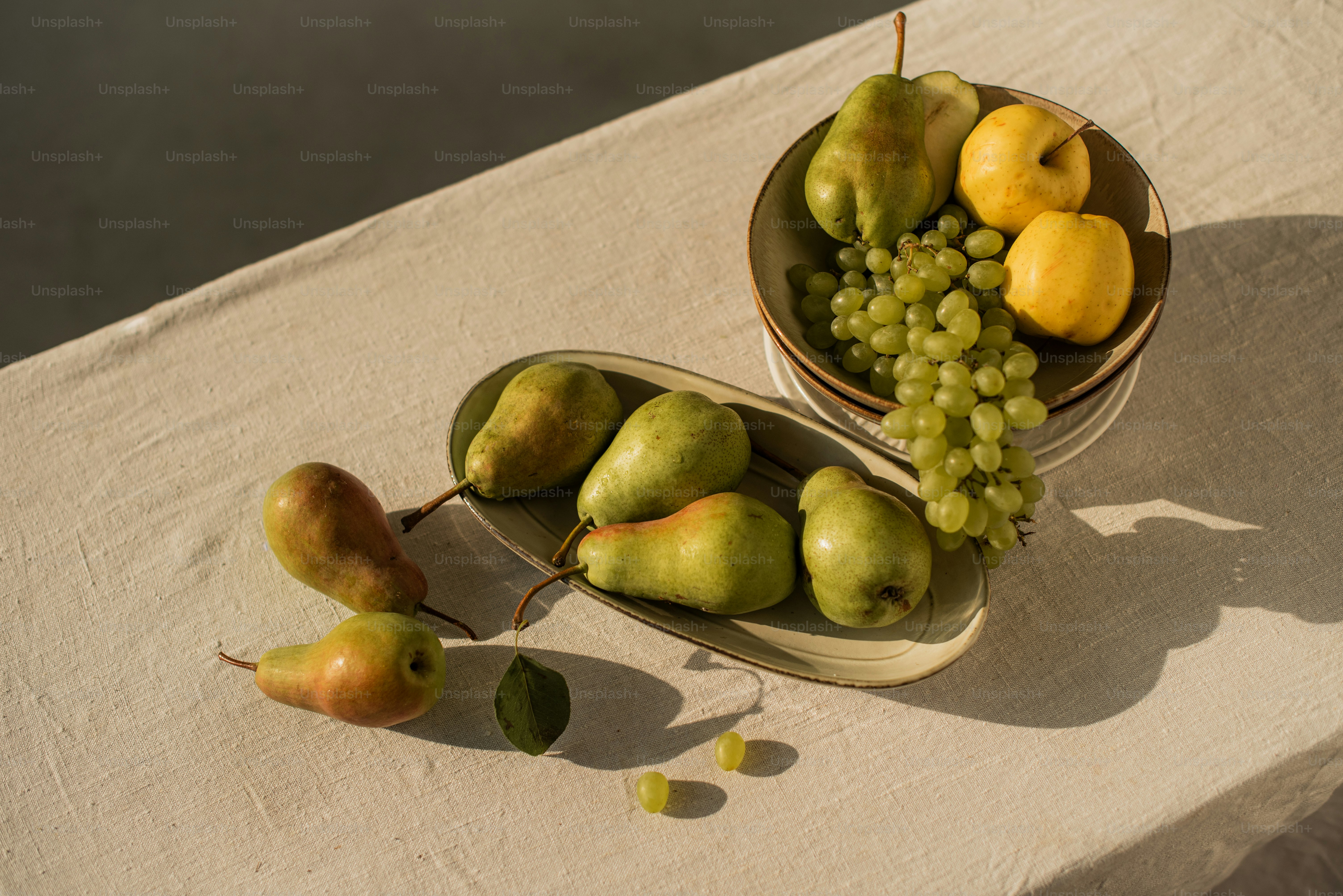 A bowl of fruit sitting on a table next to a bowl of fruit