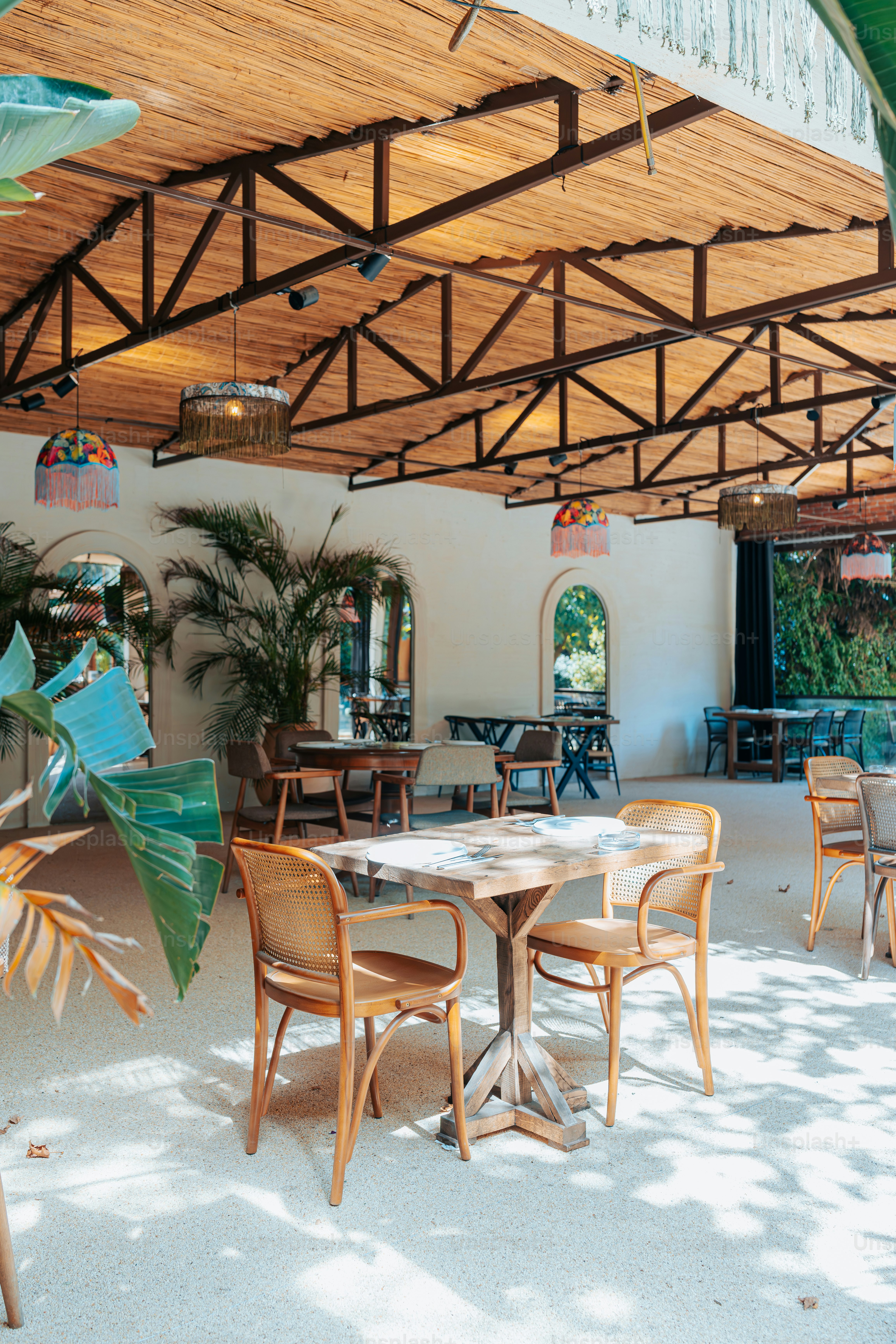 A restaurant with tables and chairs under a wooden roof