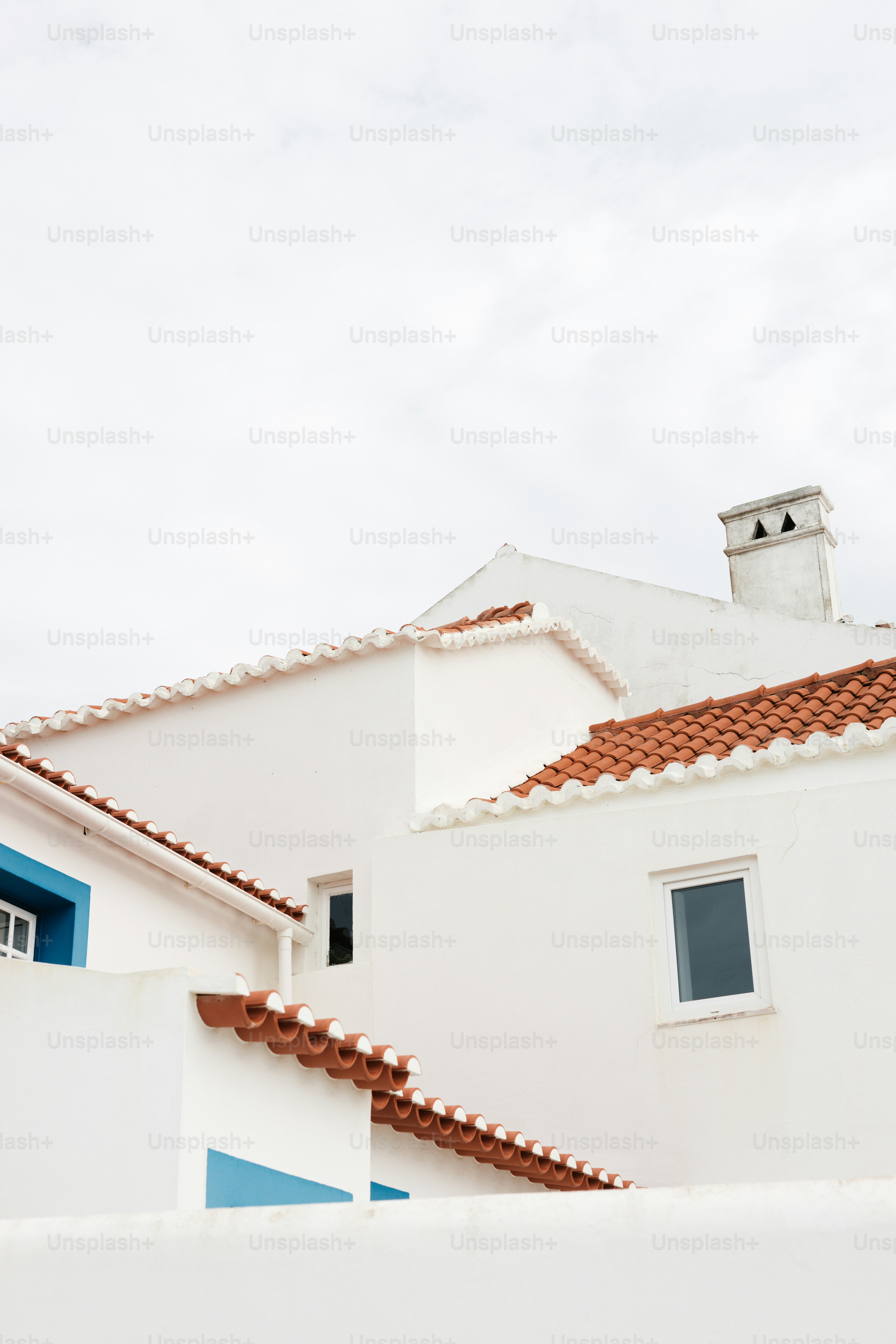 Une maison blanche aux volets bleus et au toit rouge