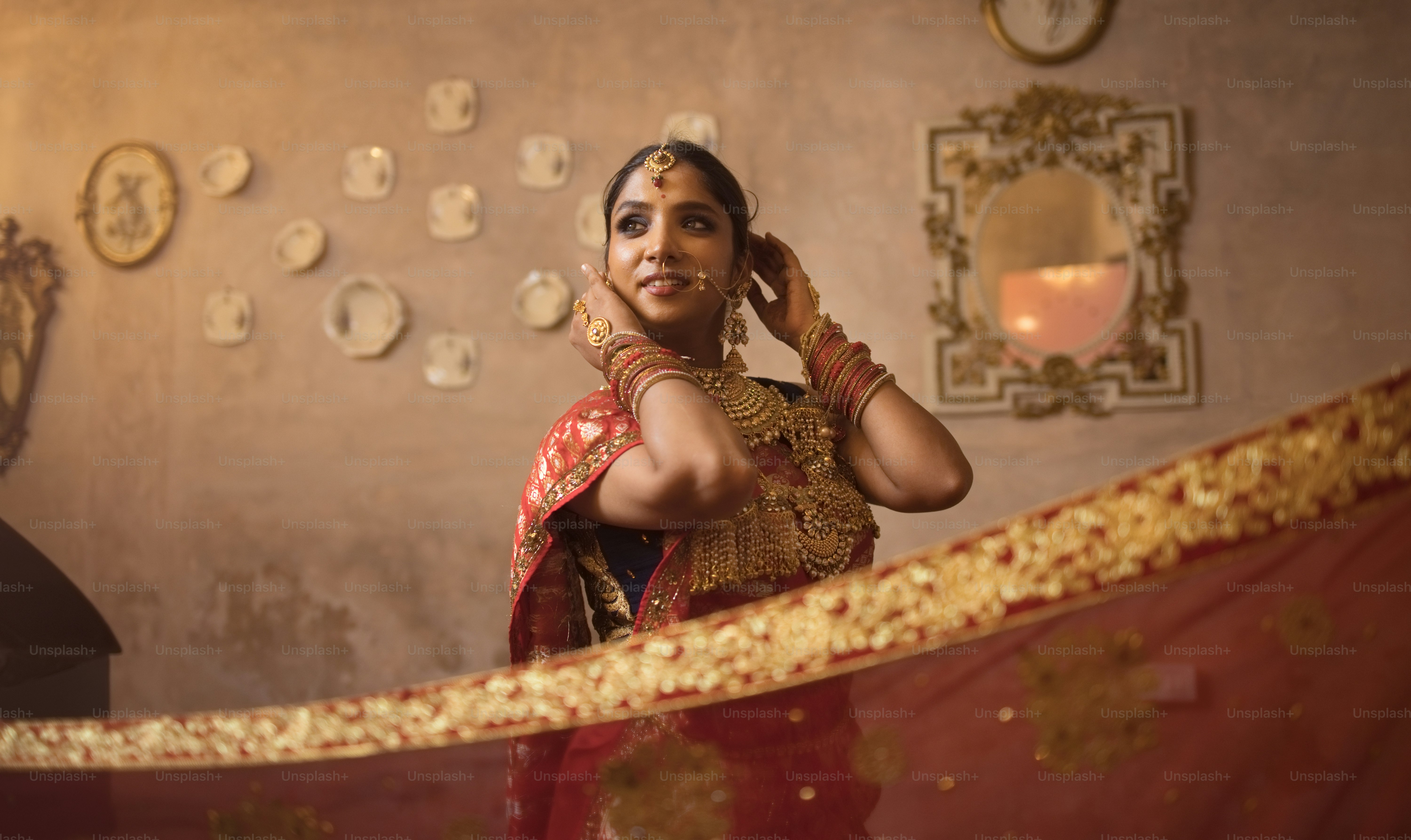 A woman in a red sari standing in front of a mirror