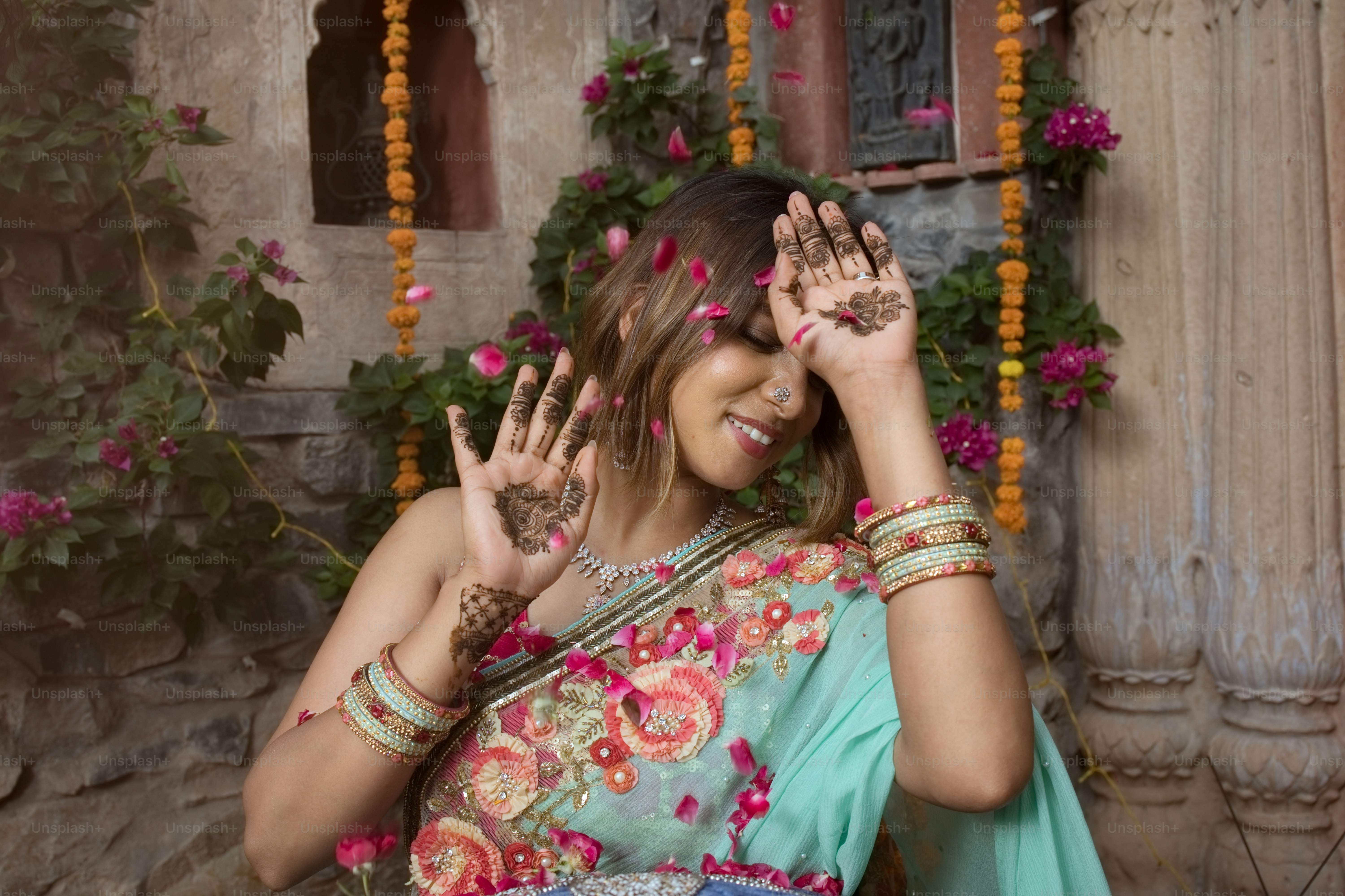 A woman in a blue sari is holding her hands up