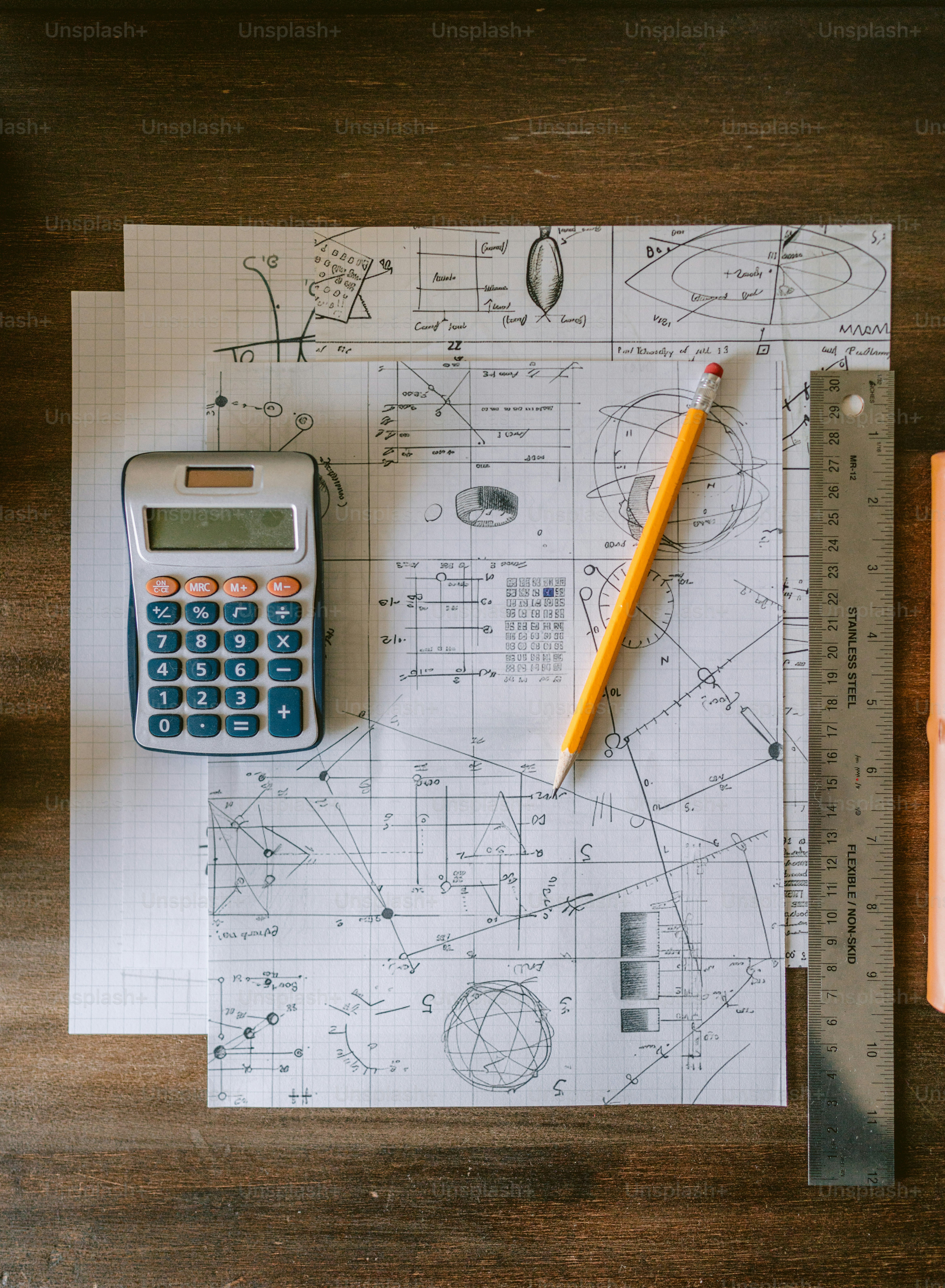 A calculator, ruler, and pencil sitting on top of a piece of