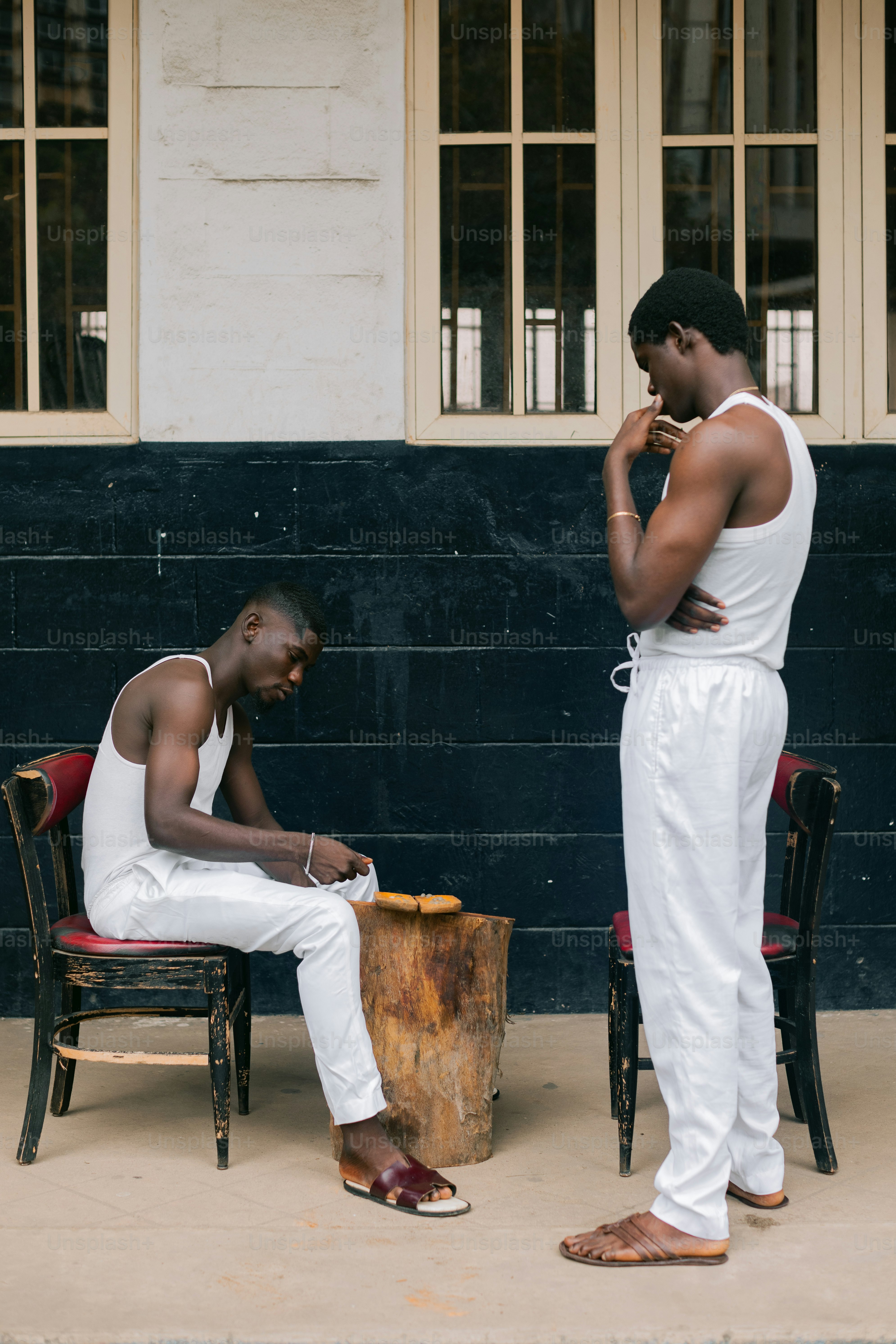 Two men sitting on chairs outside of a building