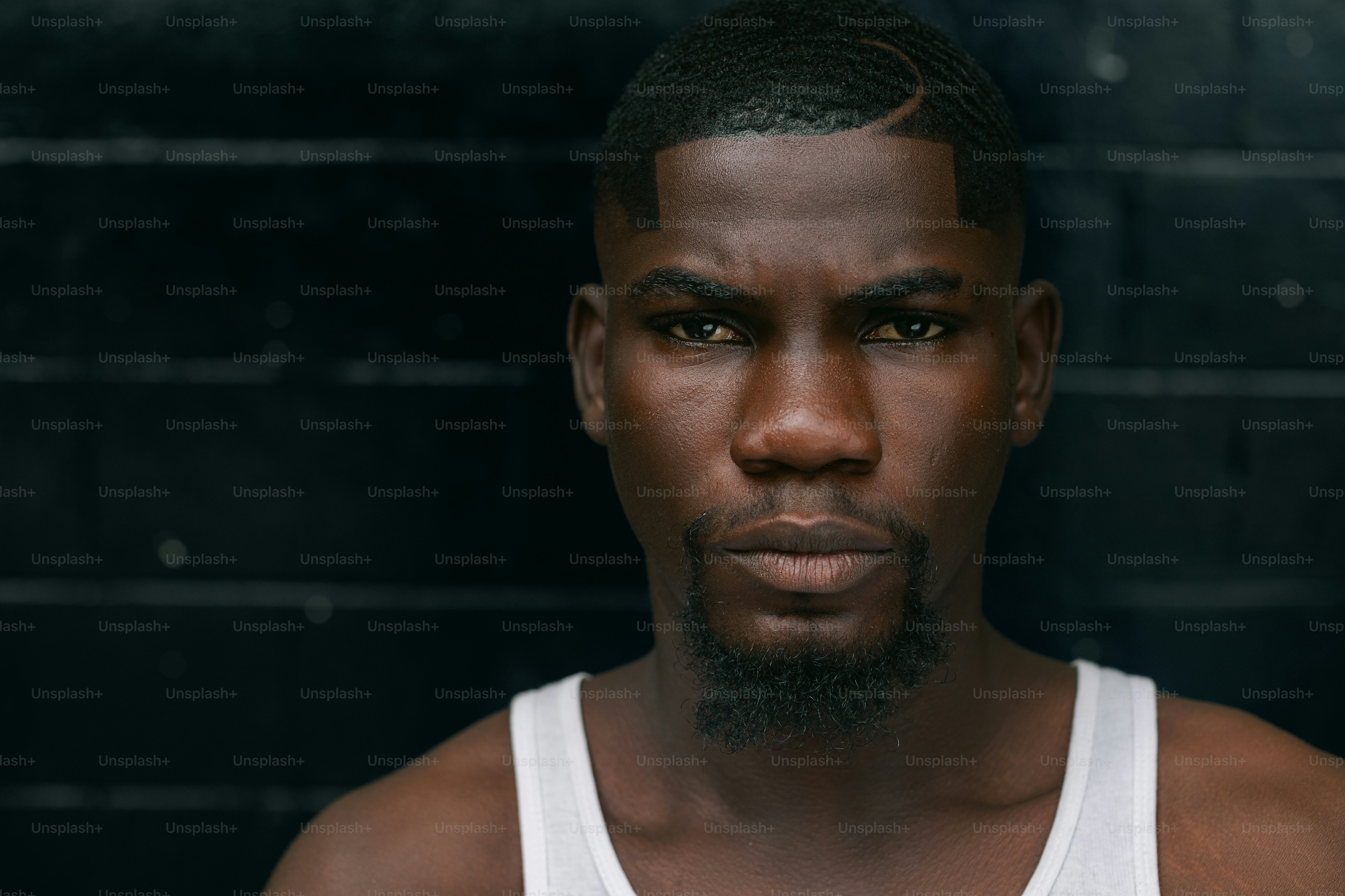 A man in a tank top standing in front of a brick wall