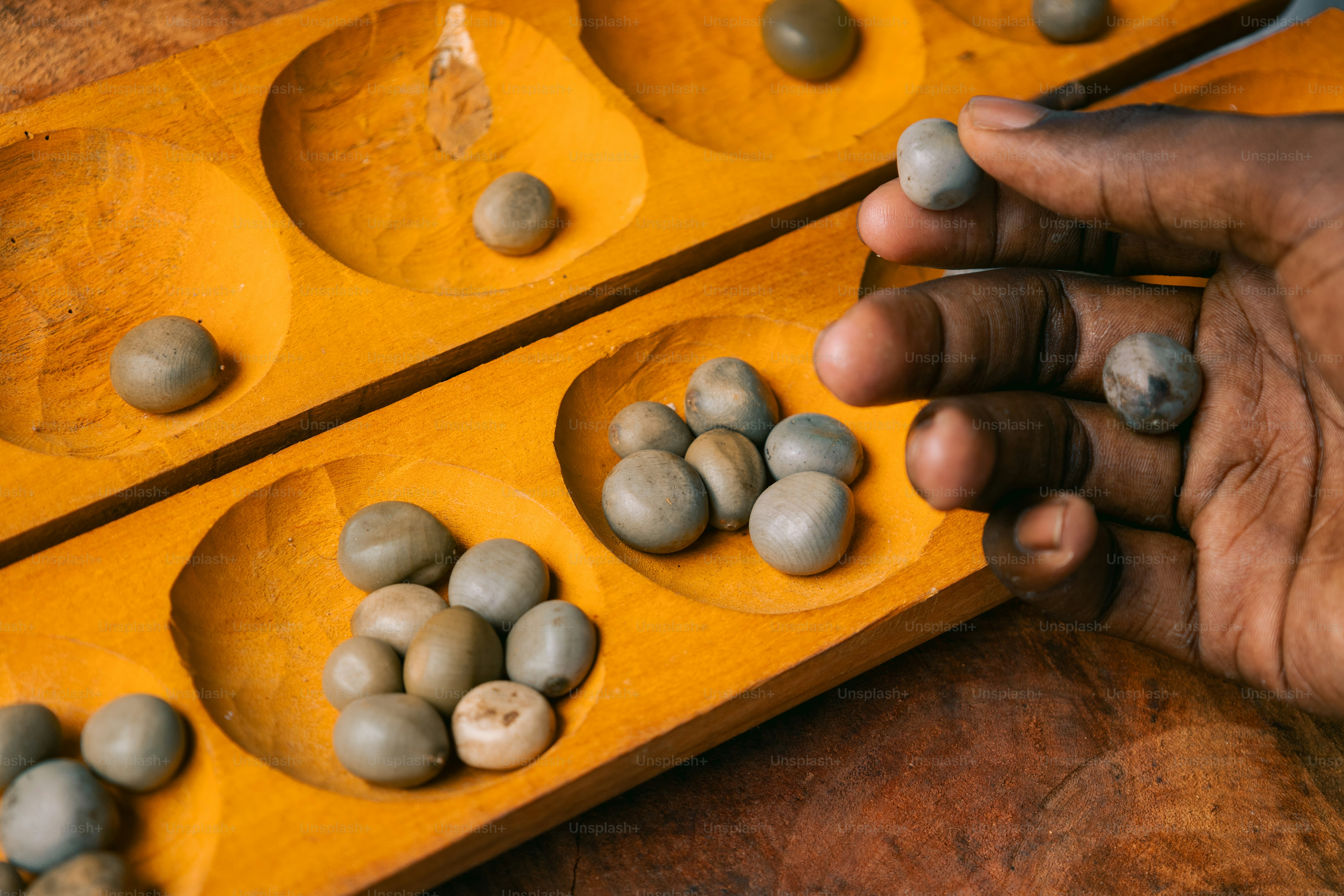 A person holding a wooden tray with rocks in it