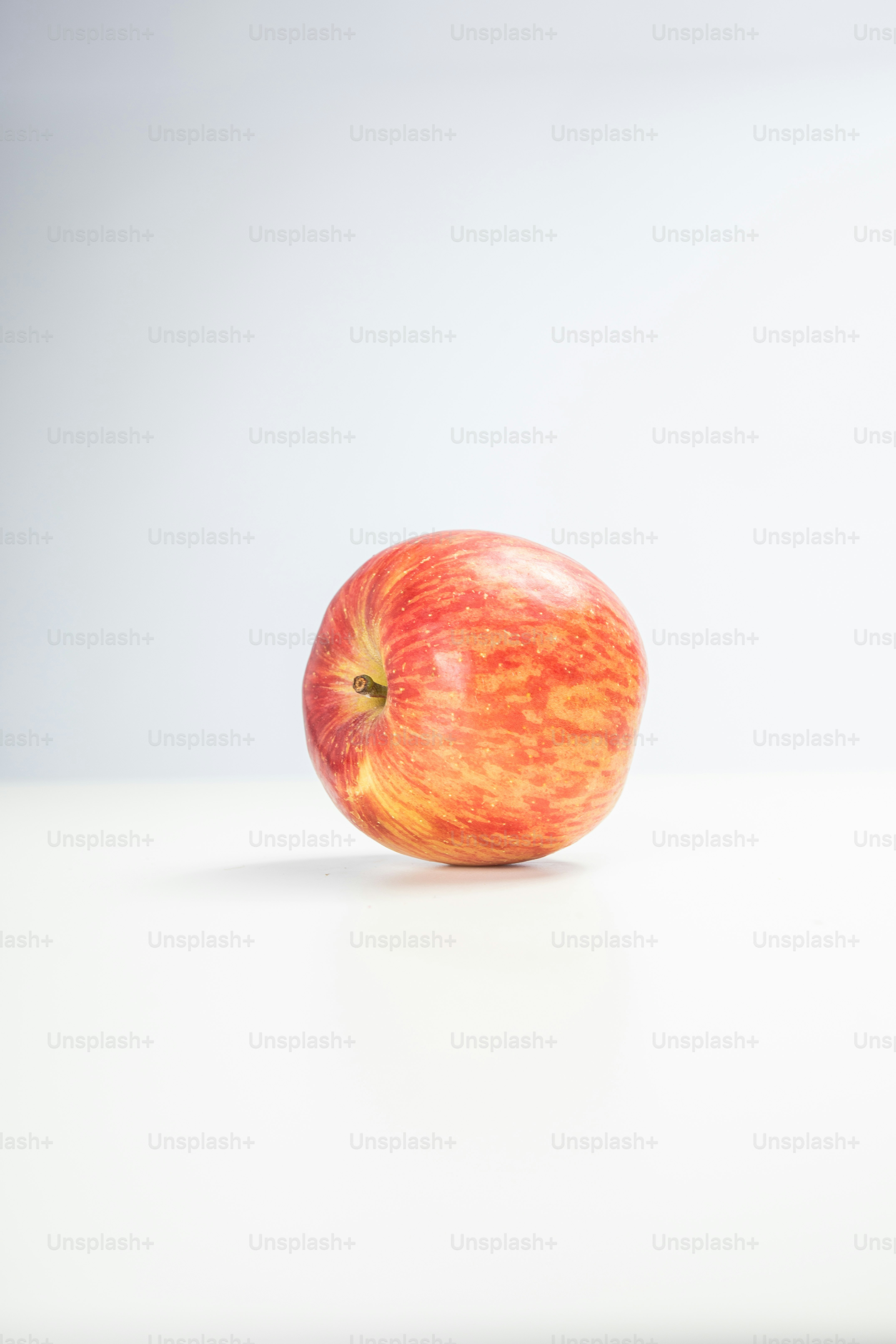 A red apple sitting on top of a white table
