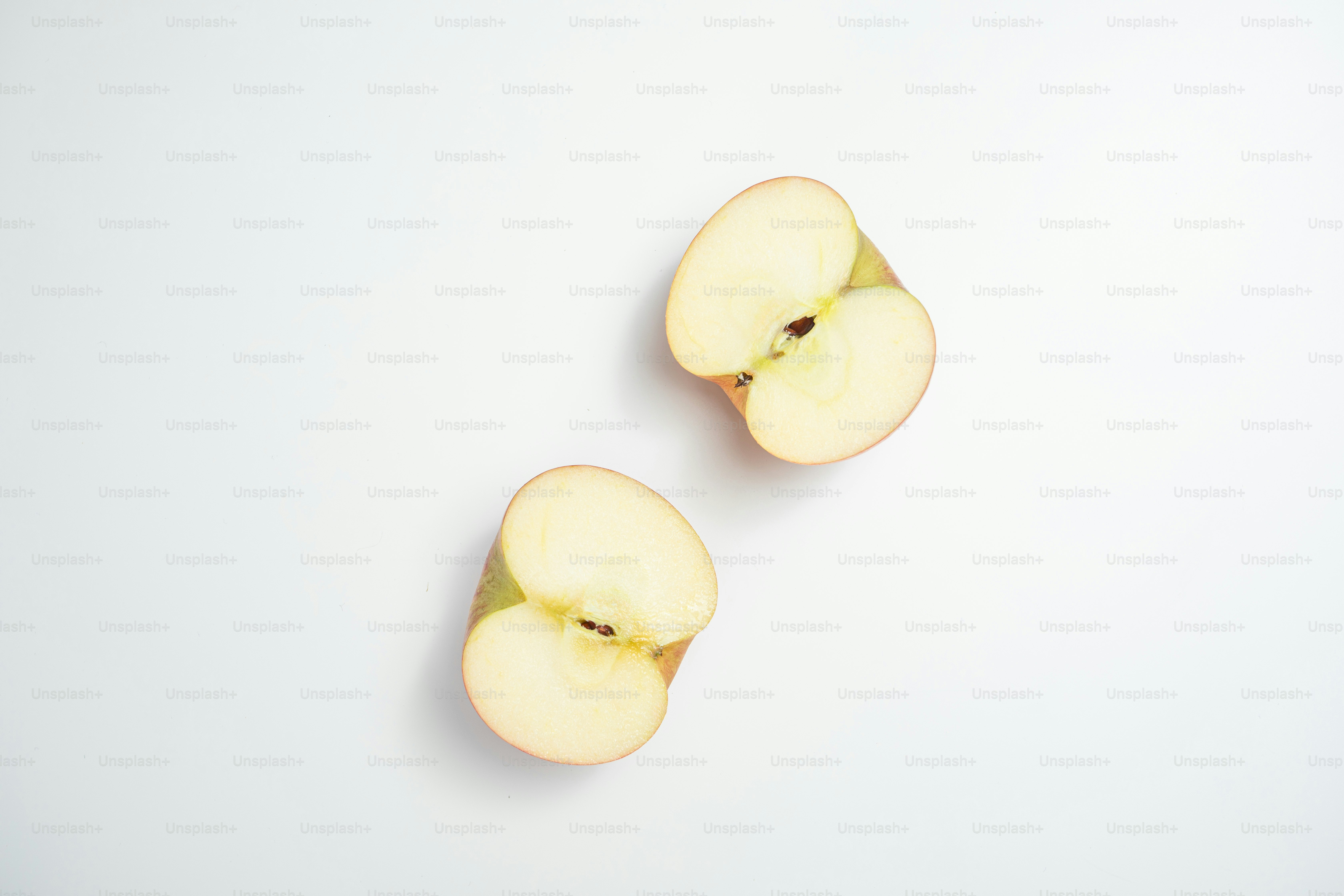 Two pieces of apple sitting on top of a white surface