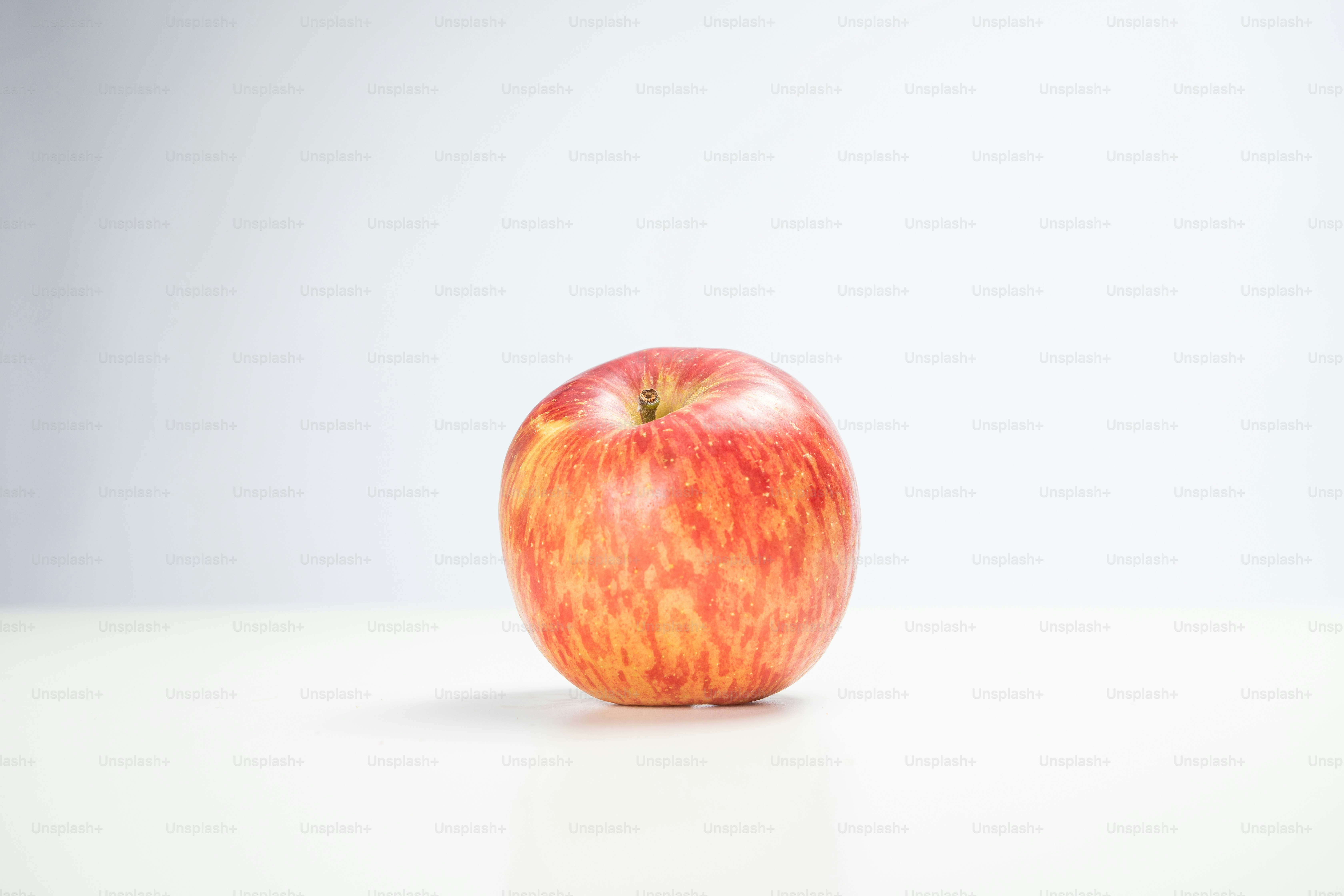 A red apple sitting on top of a white table
